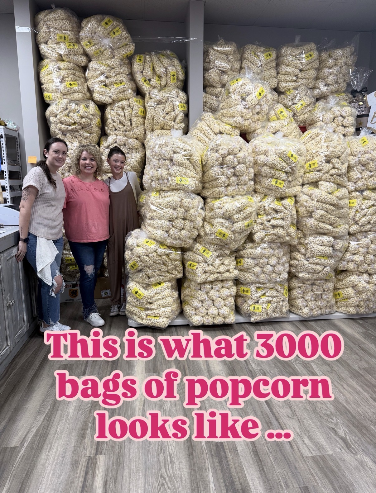 Three women standing in front of large stacks of popcorn bags in a store aisle.