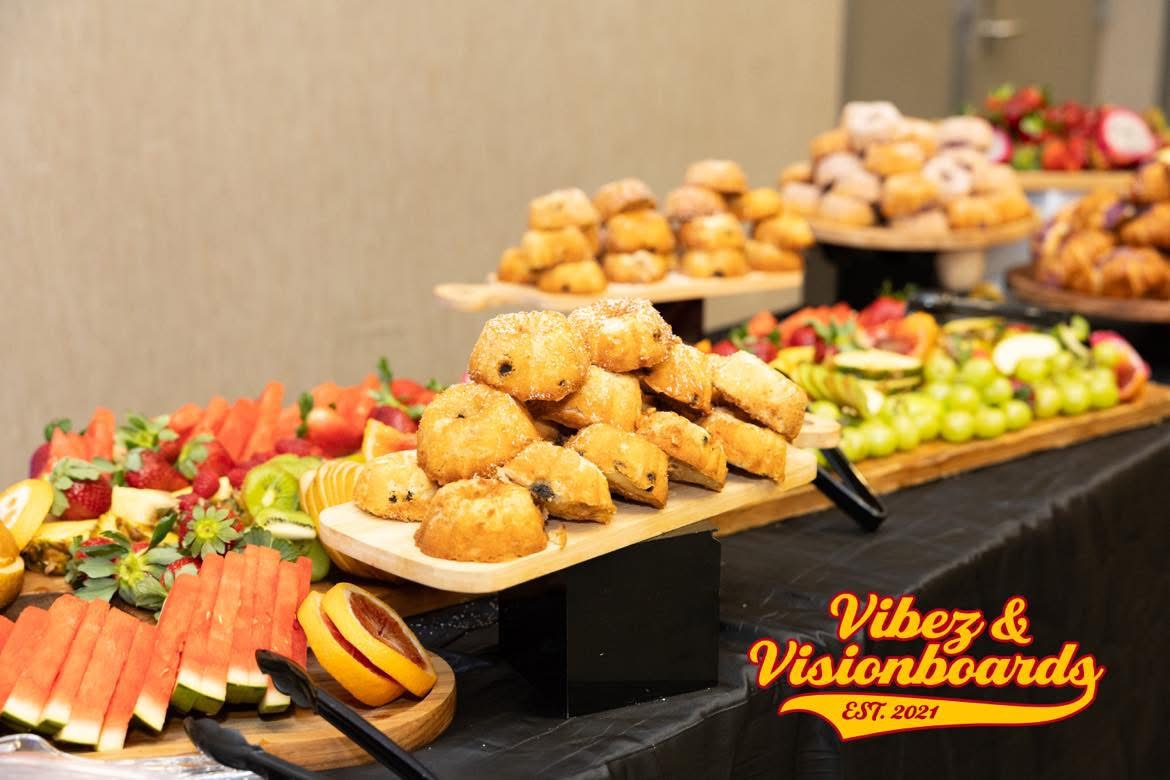 Assorted desserts and fruits on a table with a black tablecloth, including cookies, strawberries, and grapes.