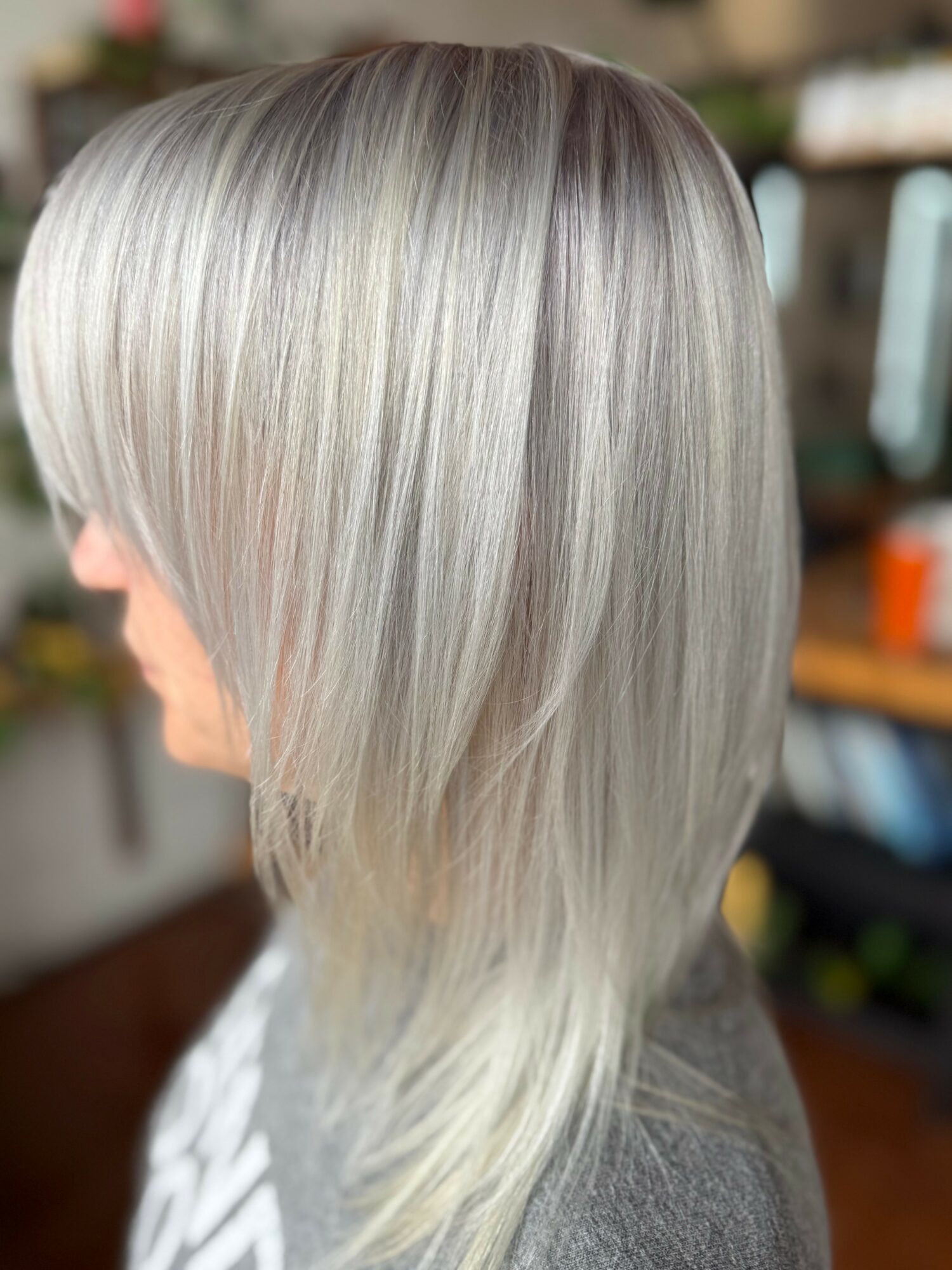Side view of a person with long, straight, silver-gray hair in a layered style.