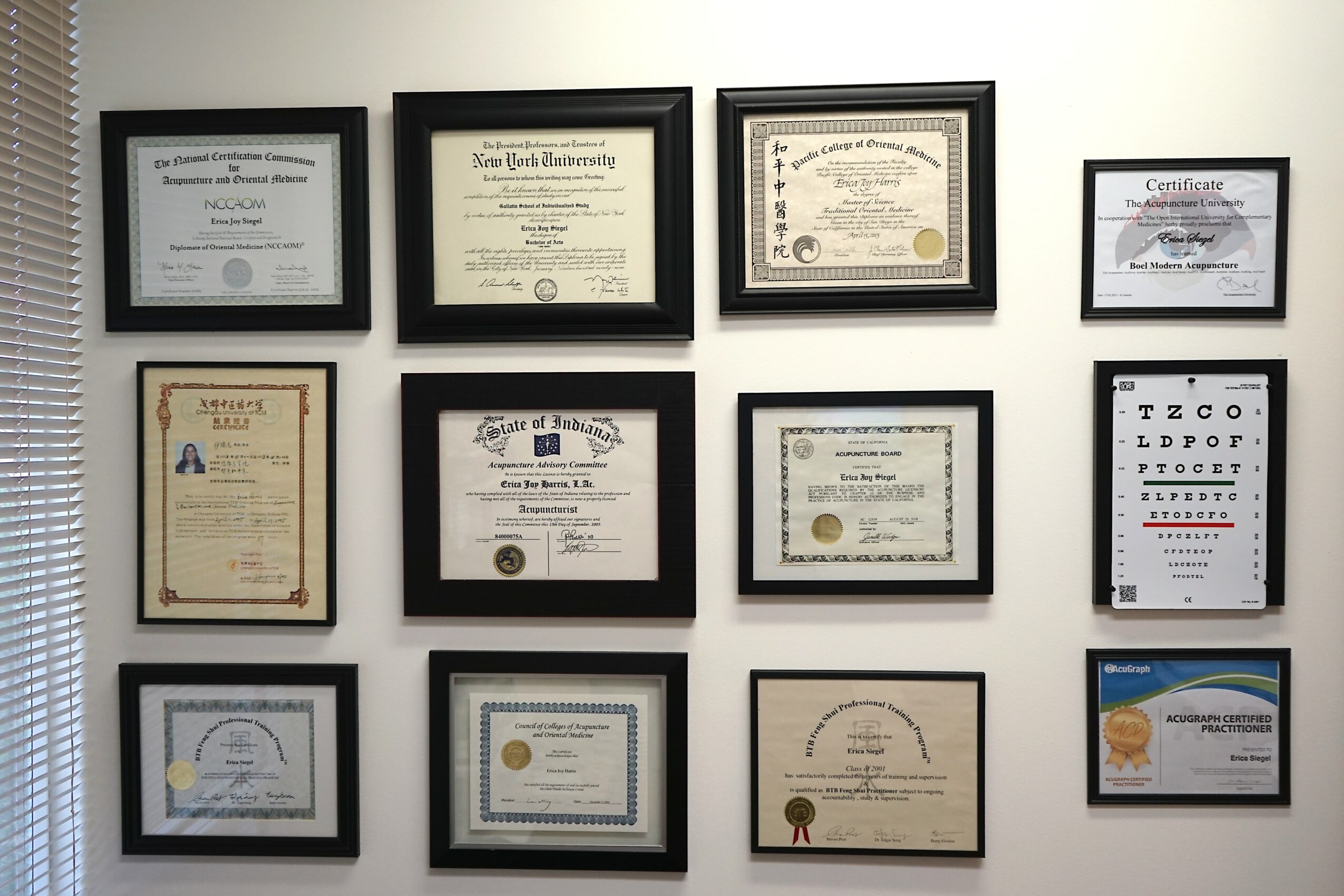 Nine framed certificates and diplomas arranged in three rows on a white wall.