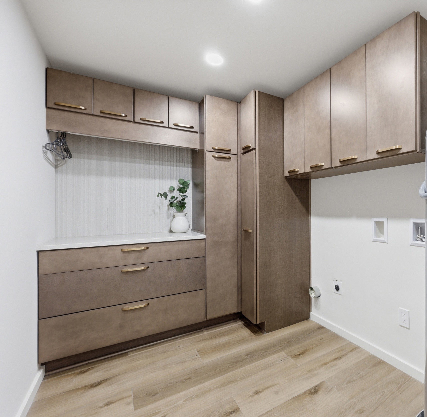 Kitchen corner with beige cabinets, a window with a plant, and a light wood floor.