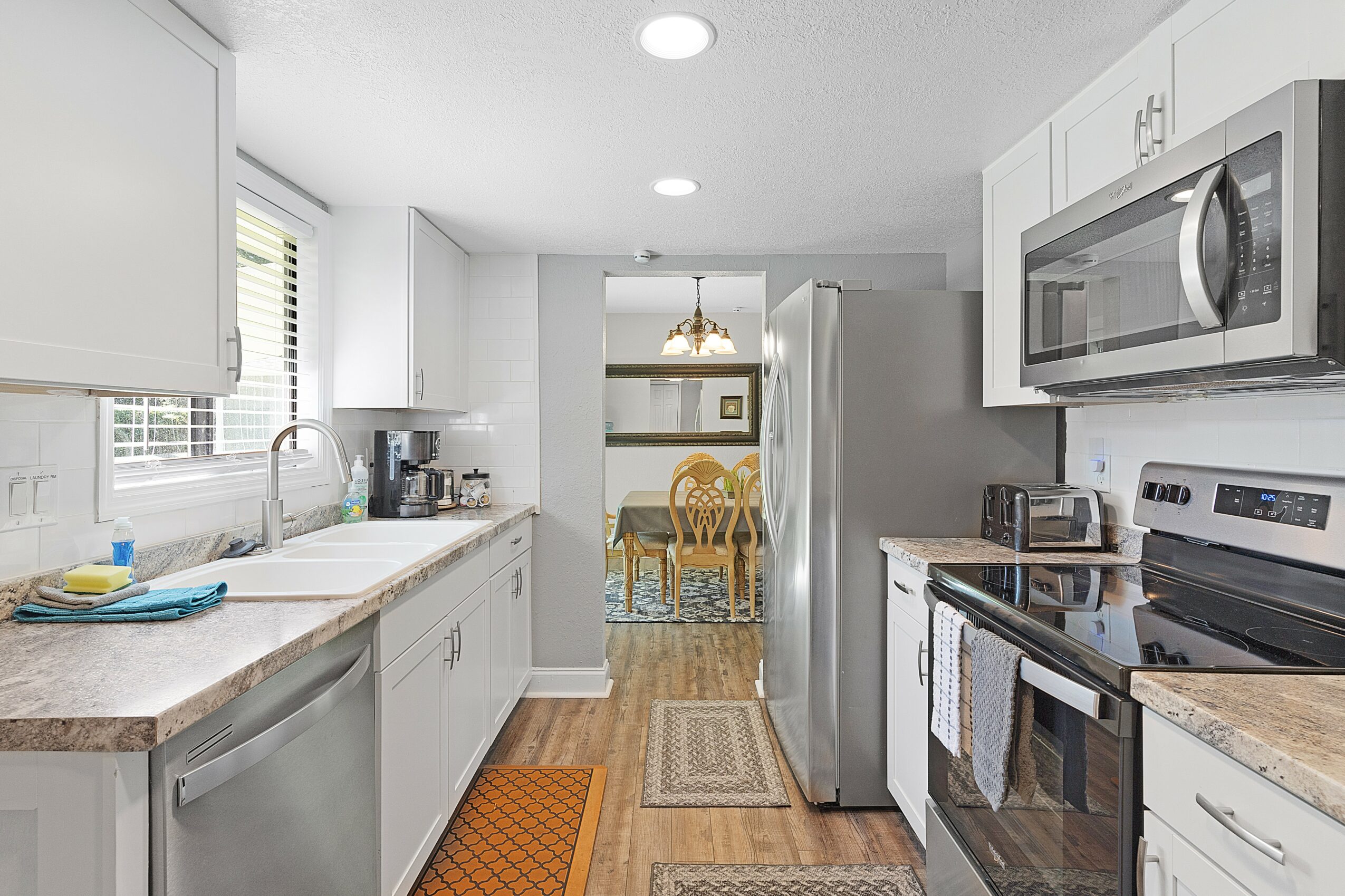 Kitchen with white cabinets, stainless steel appliances, and a dining area with a table and chairs visible in the background.