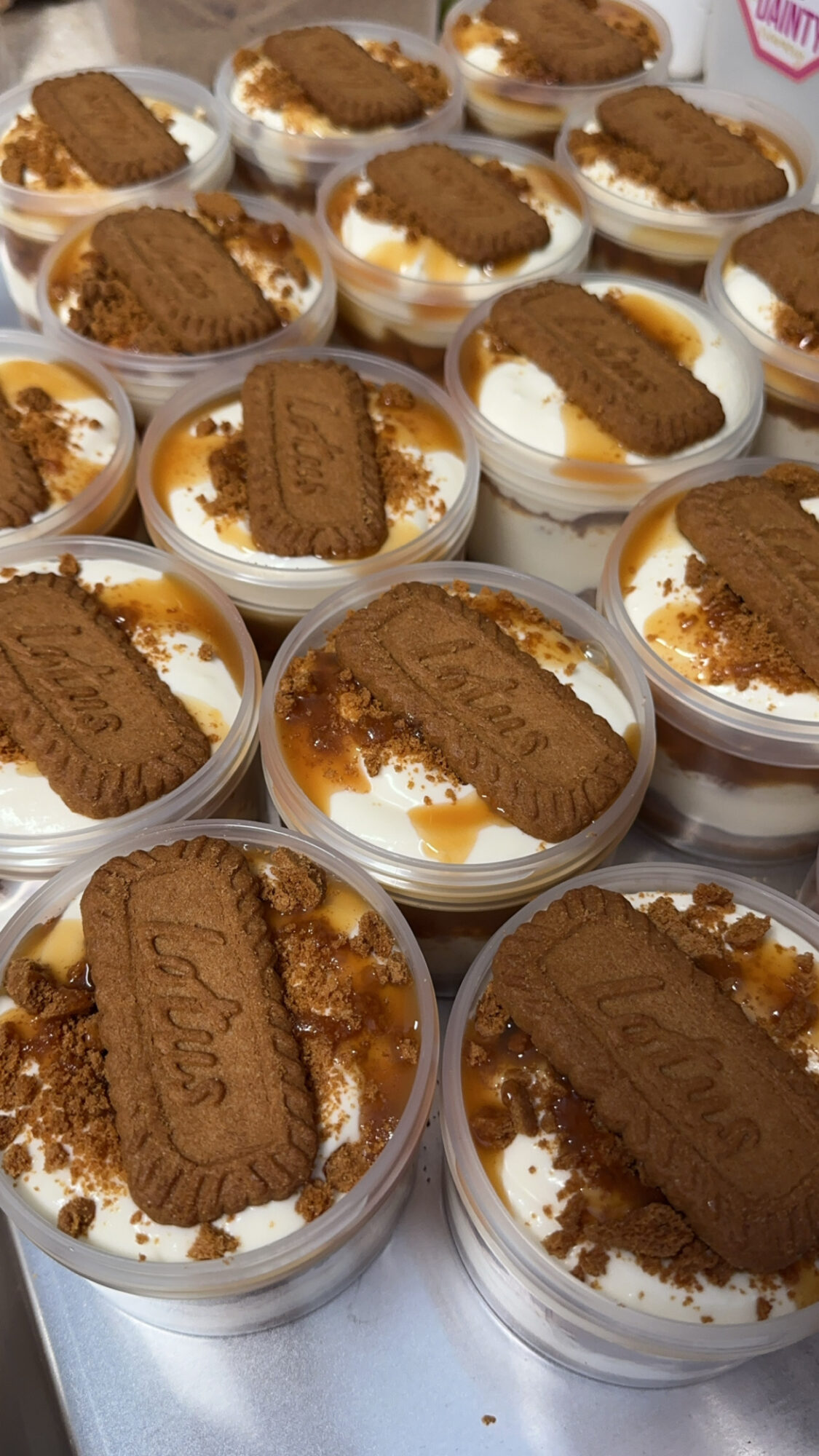 Individual dessert cups topped with Oreo cookies and crumbled cookies inside clear containers.