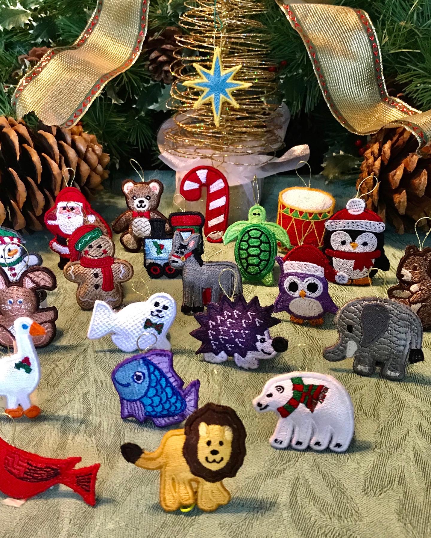 Collection of colorful felt Christmas animal ornaments including a lion, polar bear, fish, turtle, and others, arranged on a table.
