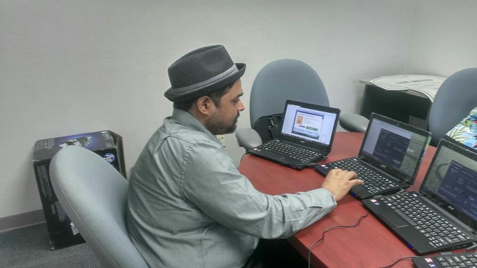 Man working at a desk with multiple laptops in an office setting.