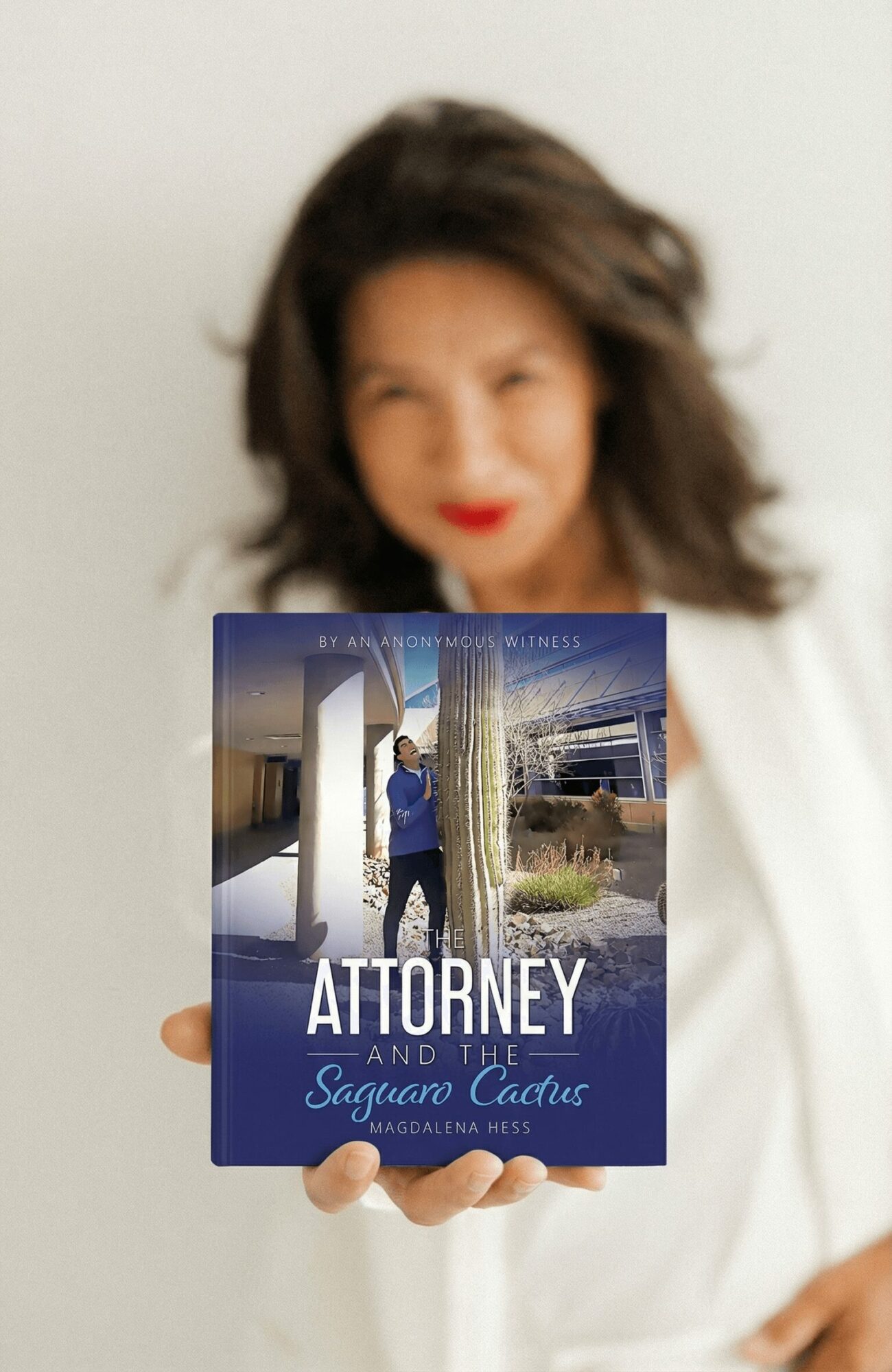 Person holding a book titled 'Attorney and the Saguaro Cactus' outdoors, with a cactus and building in background.