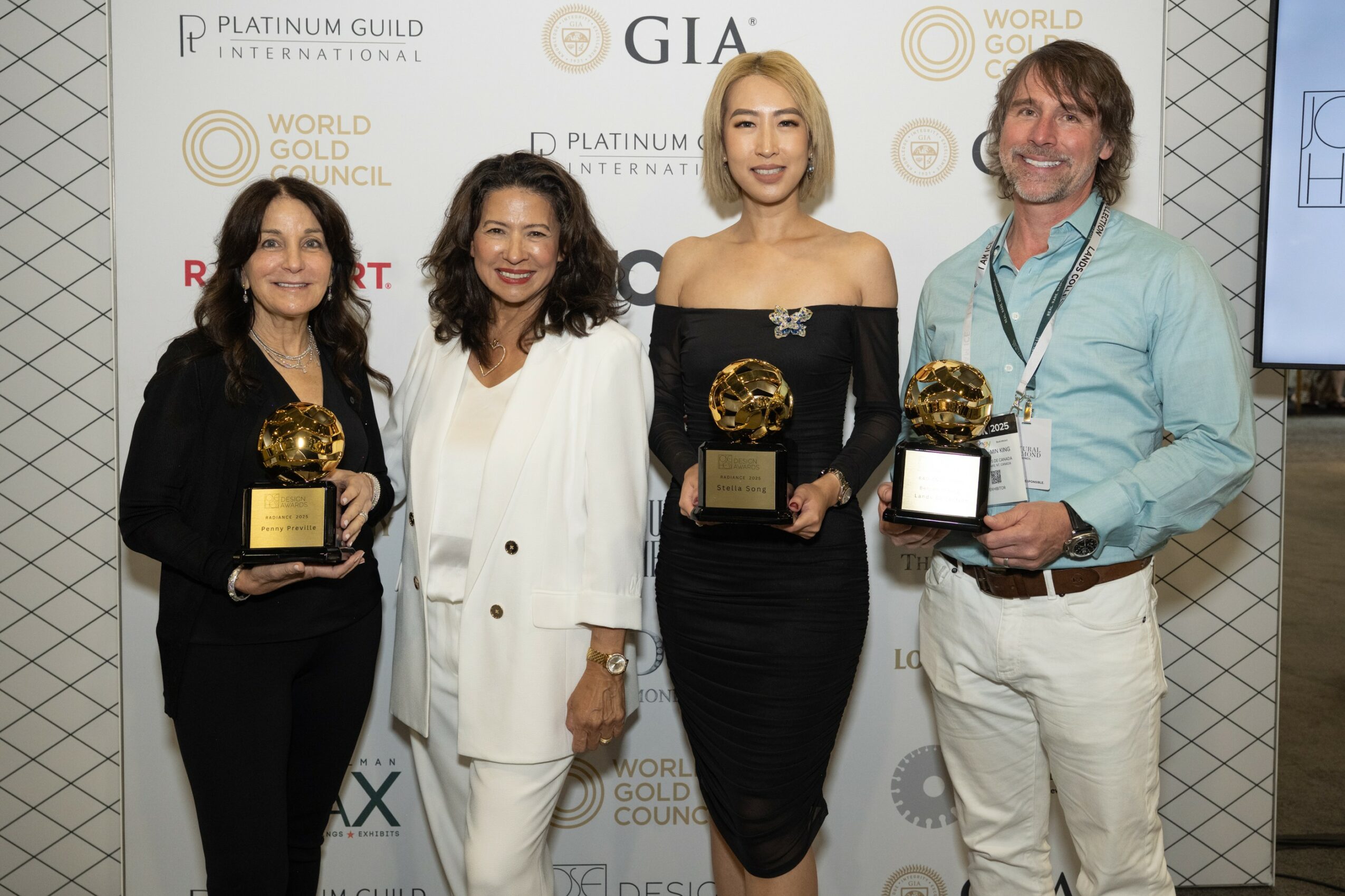 Four people standing together holding awards at an event, with a backdrop displaying logos and text.