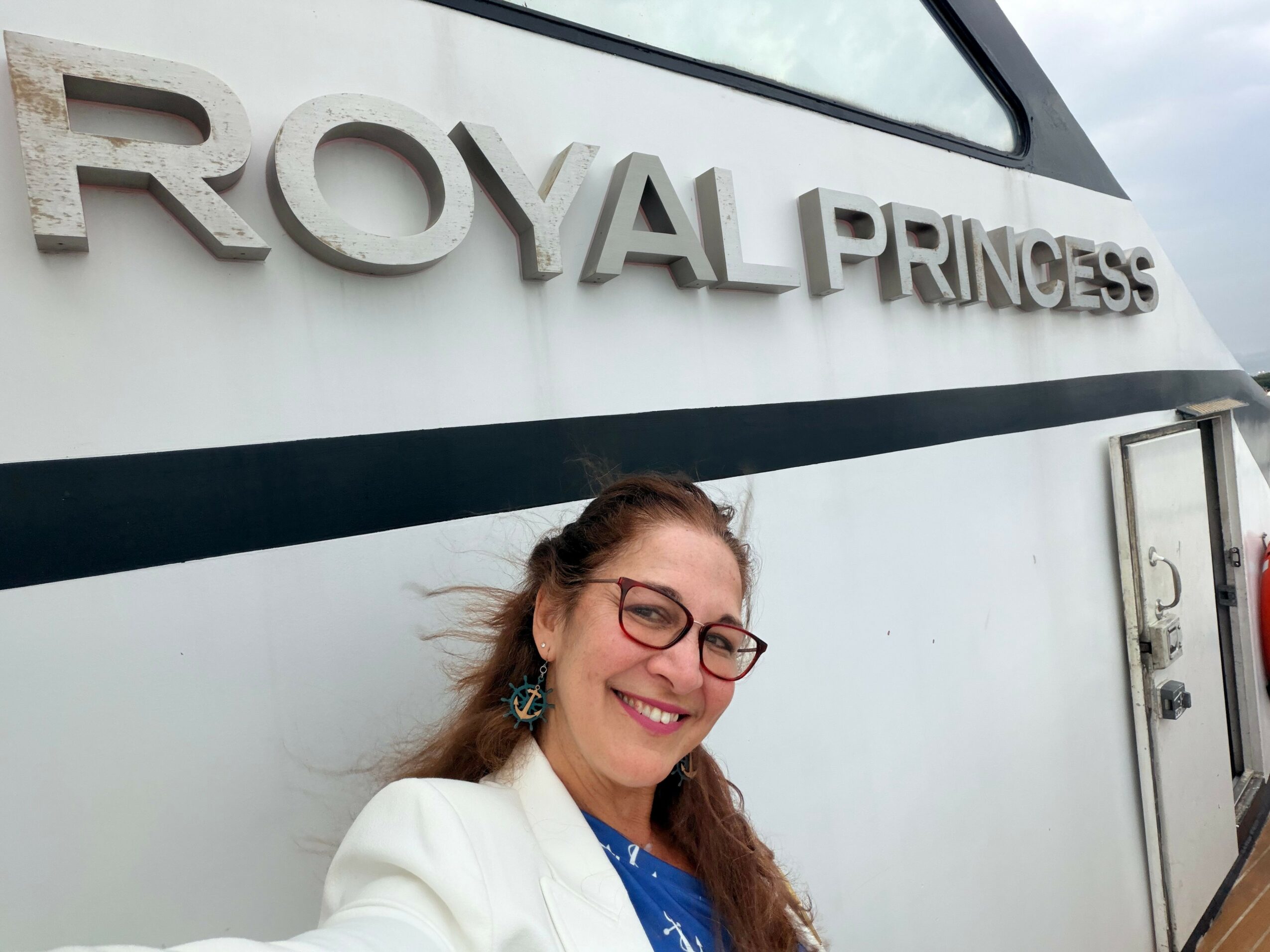 Woman with glasses smiling in front of a sign that reads 'Royal Pringles'.