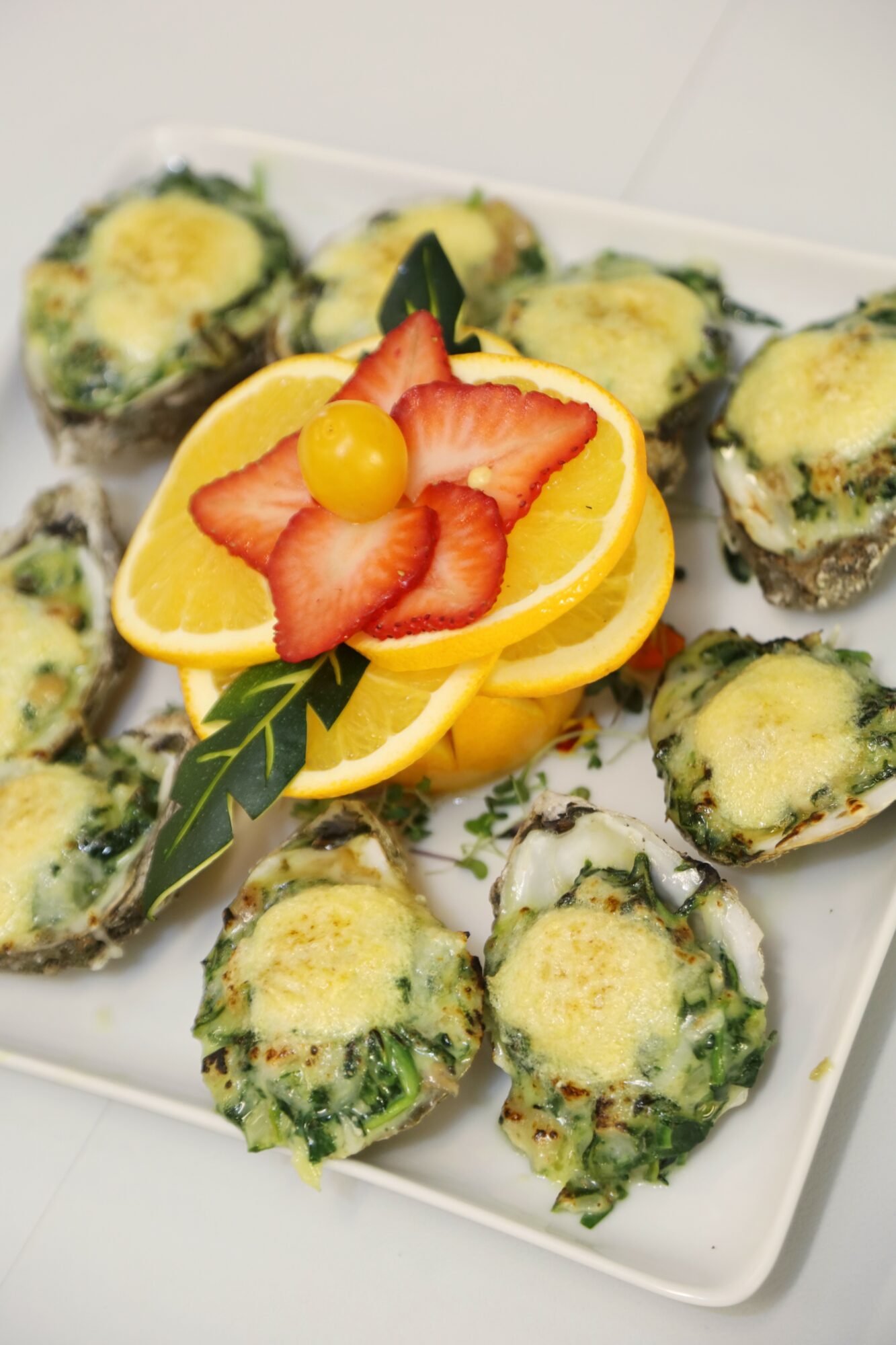 Plate of baked stuffed vegetables topped with lemon slices, strawberries, and a yellow berry, garnished with green leaves.