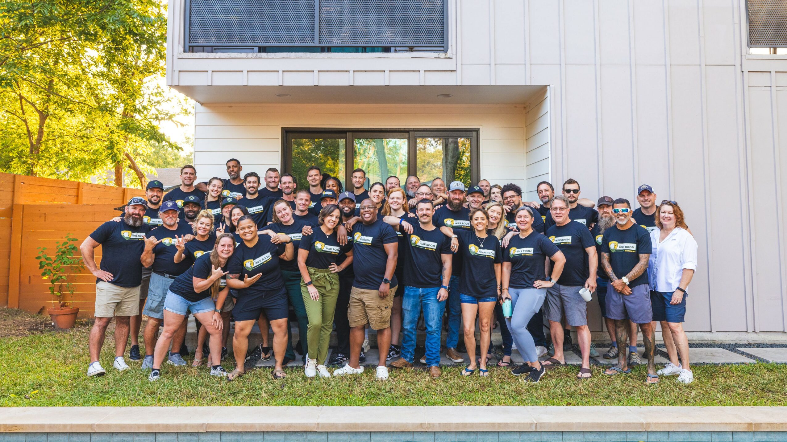 Group of people standing outside in front of a modern building, smiling and posing for a photo.