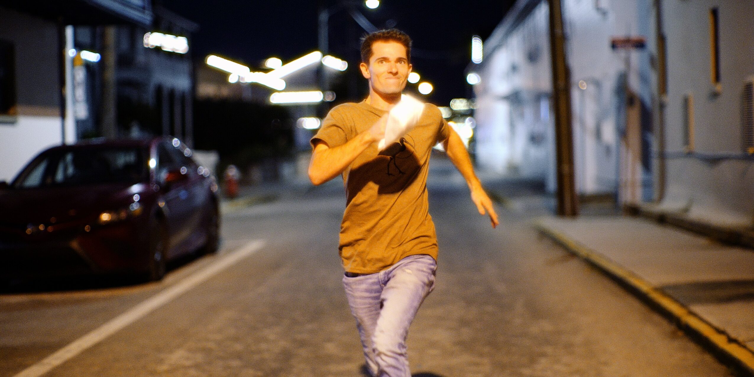 Person running on a city street at night, wearing a yellow shirt and light-colored pants.