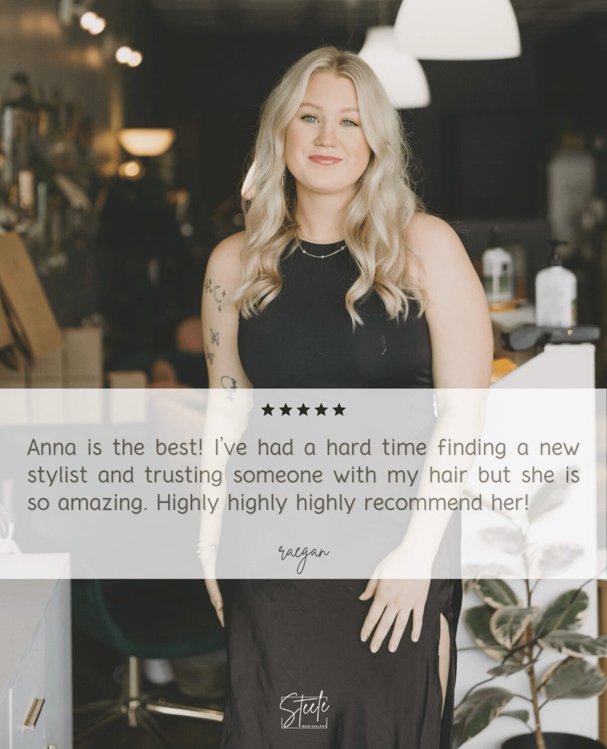 Woman with long blonde hair in a black dress smiling in a modern indoor setting.