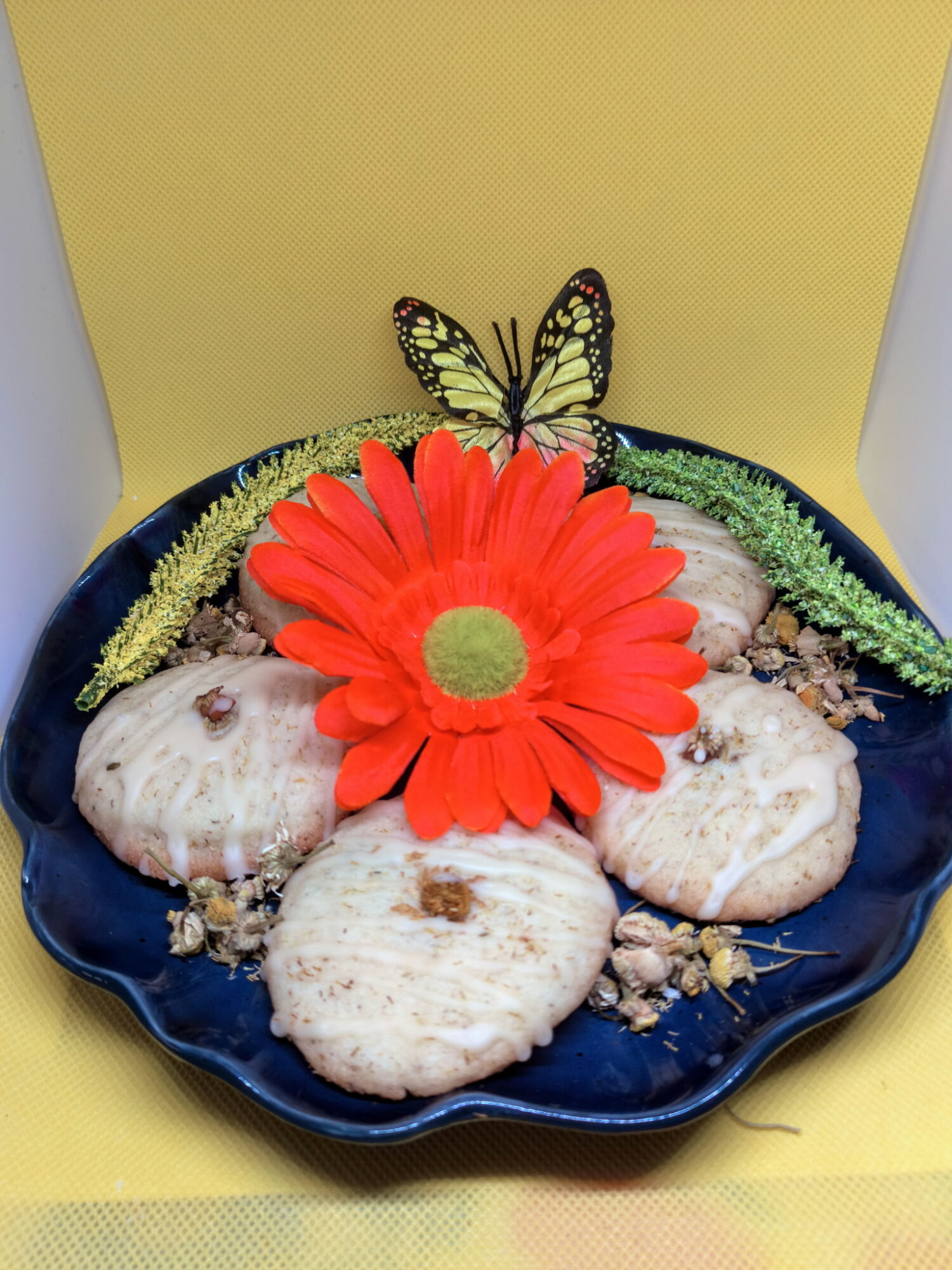 Decorative plate with seashells, a large red flower, a butterfly, and green and yellow accents, set against a yellow background.