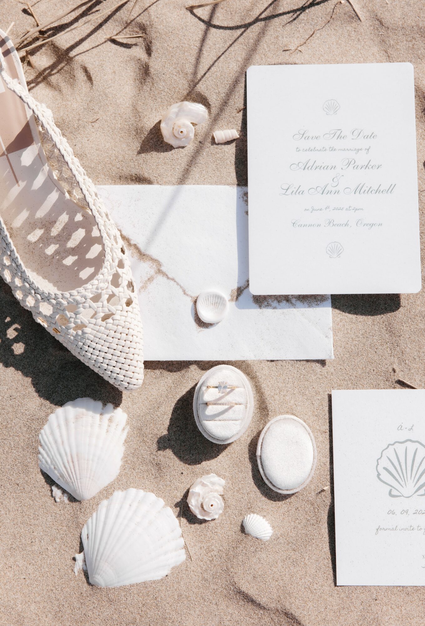 Beach scene with seashells, a white shoe, and a wedding invitation on sand.