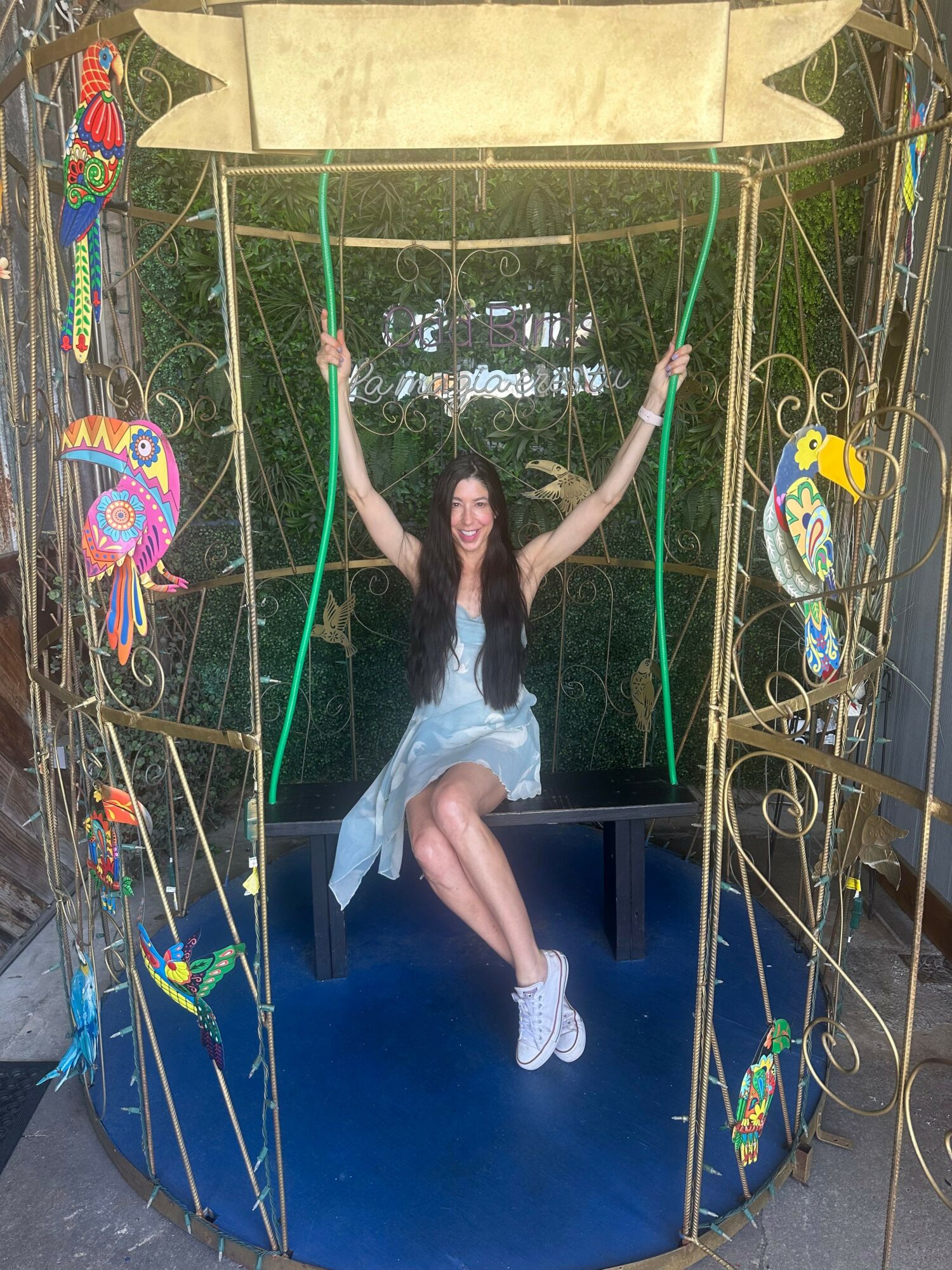 Person in a white dress on a swing with colorful decorations, outdoors, with a blue background and grass.