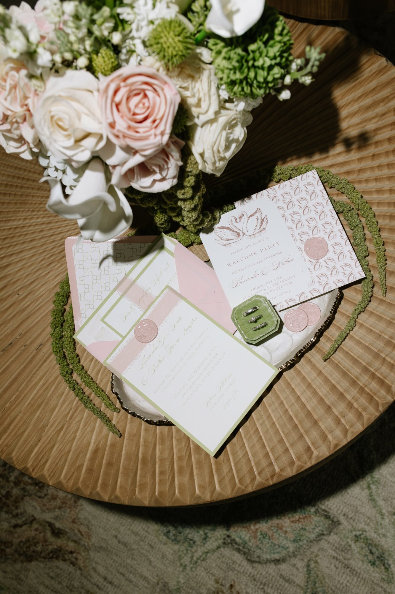 Open greeting card on a wooden table with a bouquet of flowers nearby, surrounded by a green circular mat.