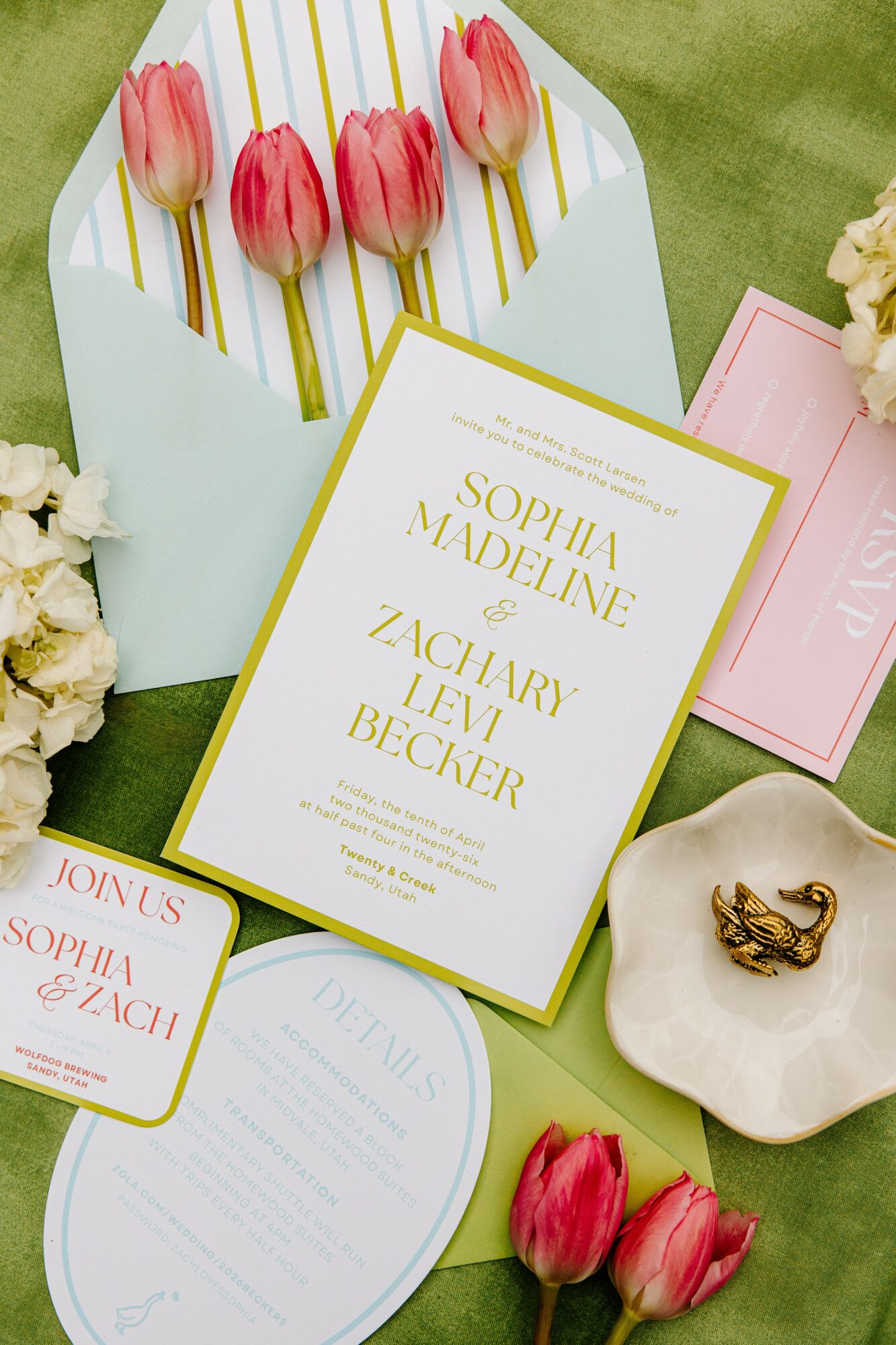 Wedding invitation with pink tulips, a gold ring, and floral decorations on a green background.
