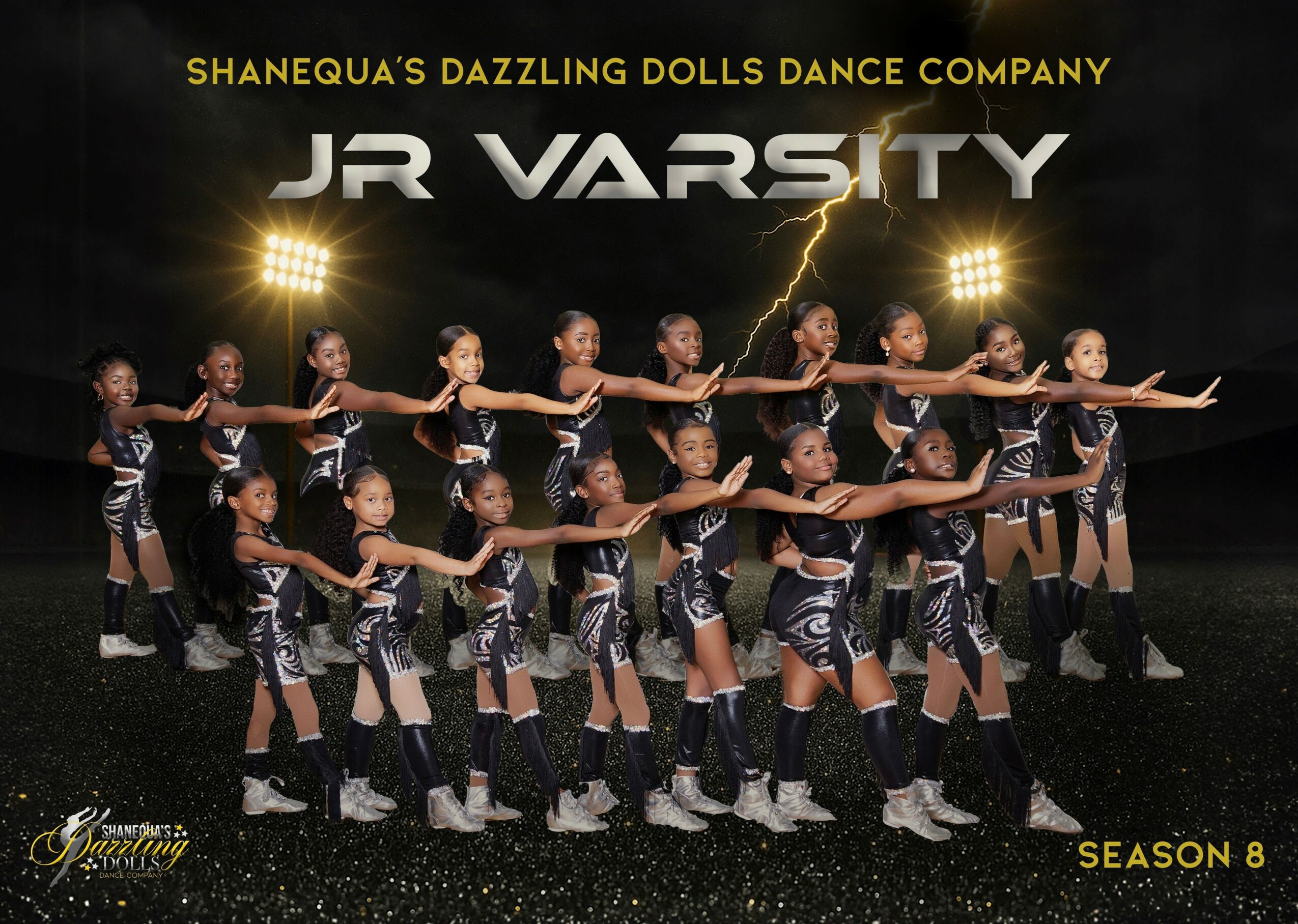 Group of young dancers in matching costumes perform on stage with stadium lights in background.