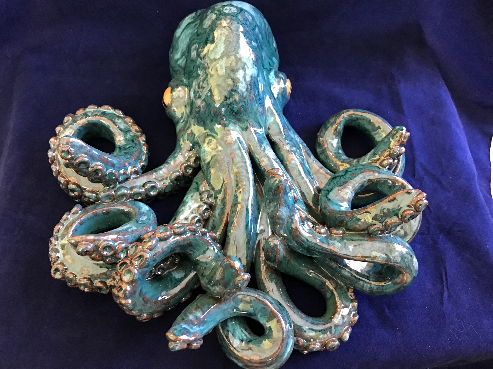 Decorative octopus sculpture with detailed tentacles, placed on dark fabric background.