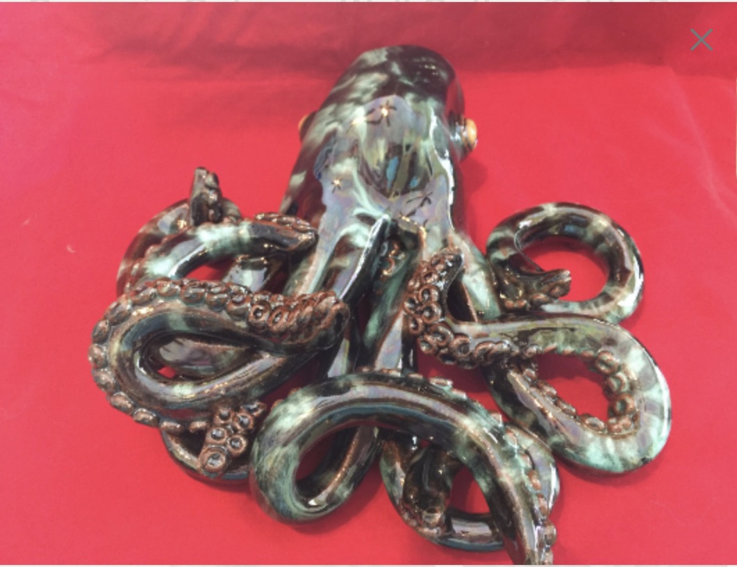A metallic octopus sculpture with detailed tentacles on a red background.