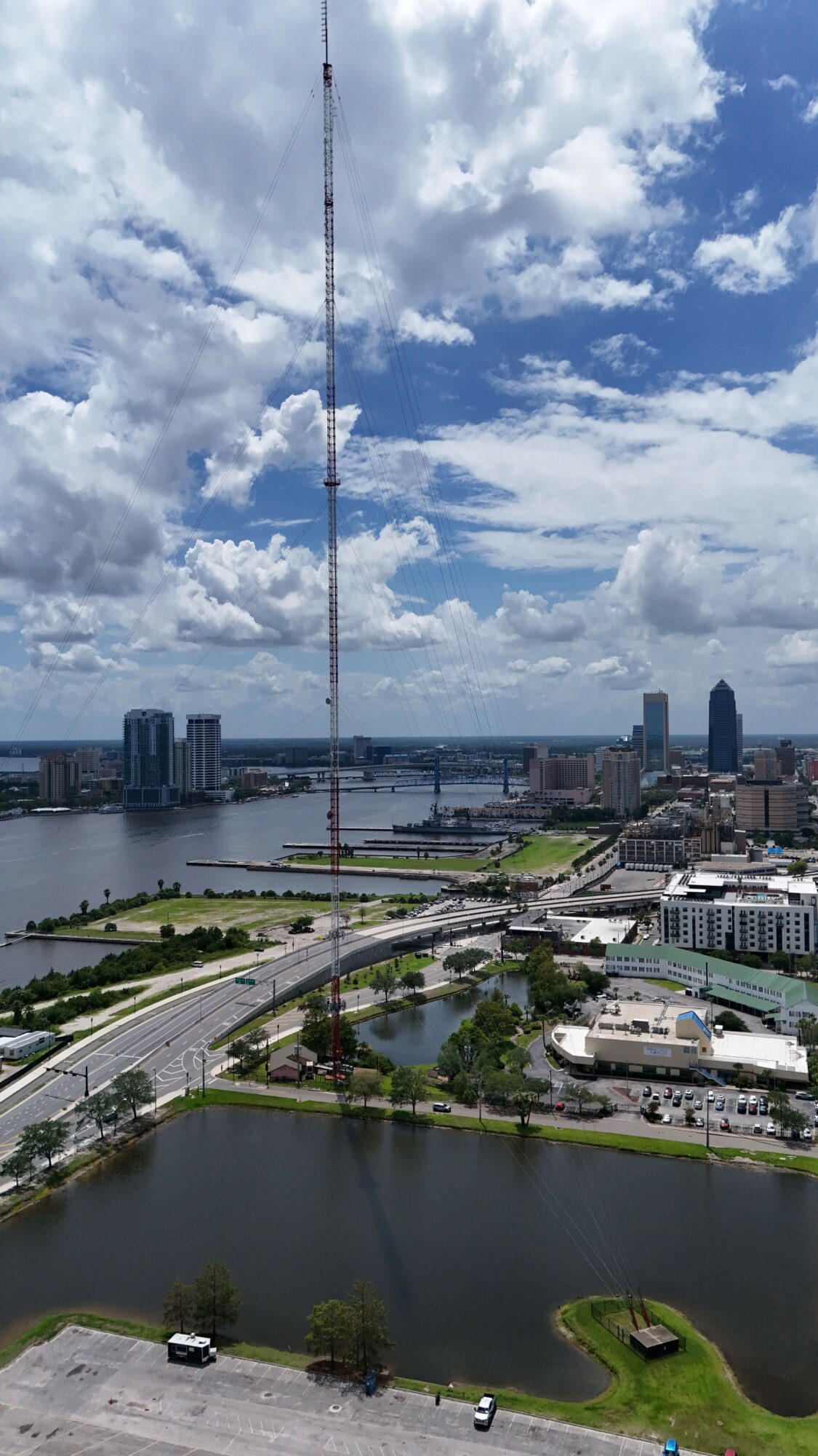 Cityscape with river, bridges, and tall buildings under a partly cloudy sky.