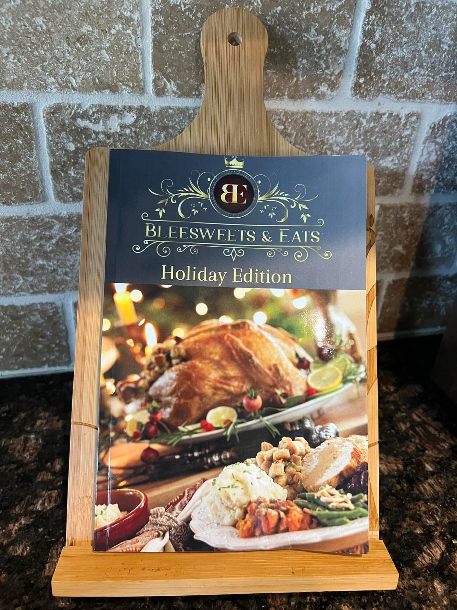 Menu board with a wooden handle displaying a roasted turkey and side dishes, against a brick wall background.