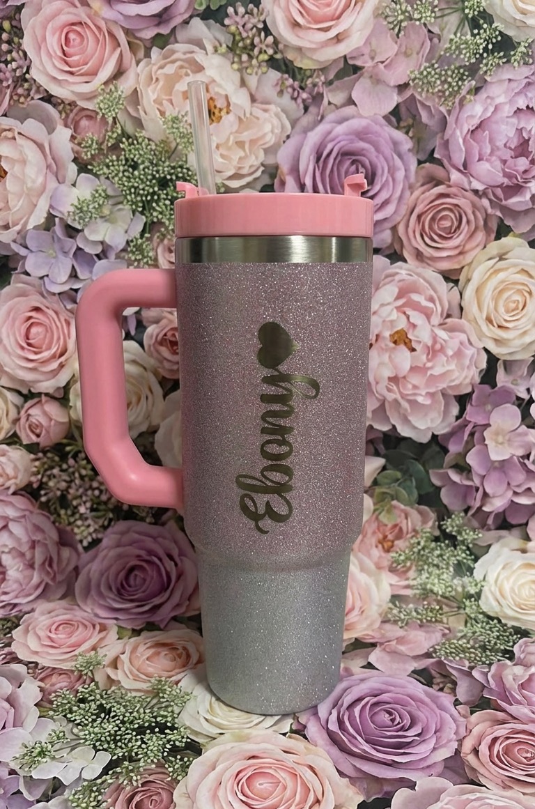 Pink and gray floral-patterned travel mug with a pink handle and lid, set against a background of roses.