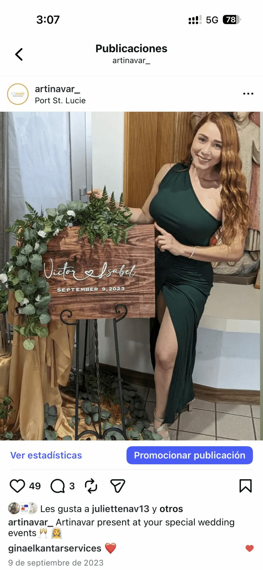 Woman in green dress standing next to a wedding sign with flowers, smiling indoors.