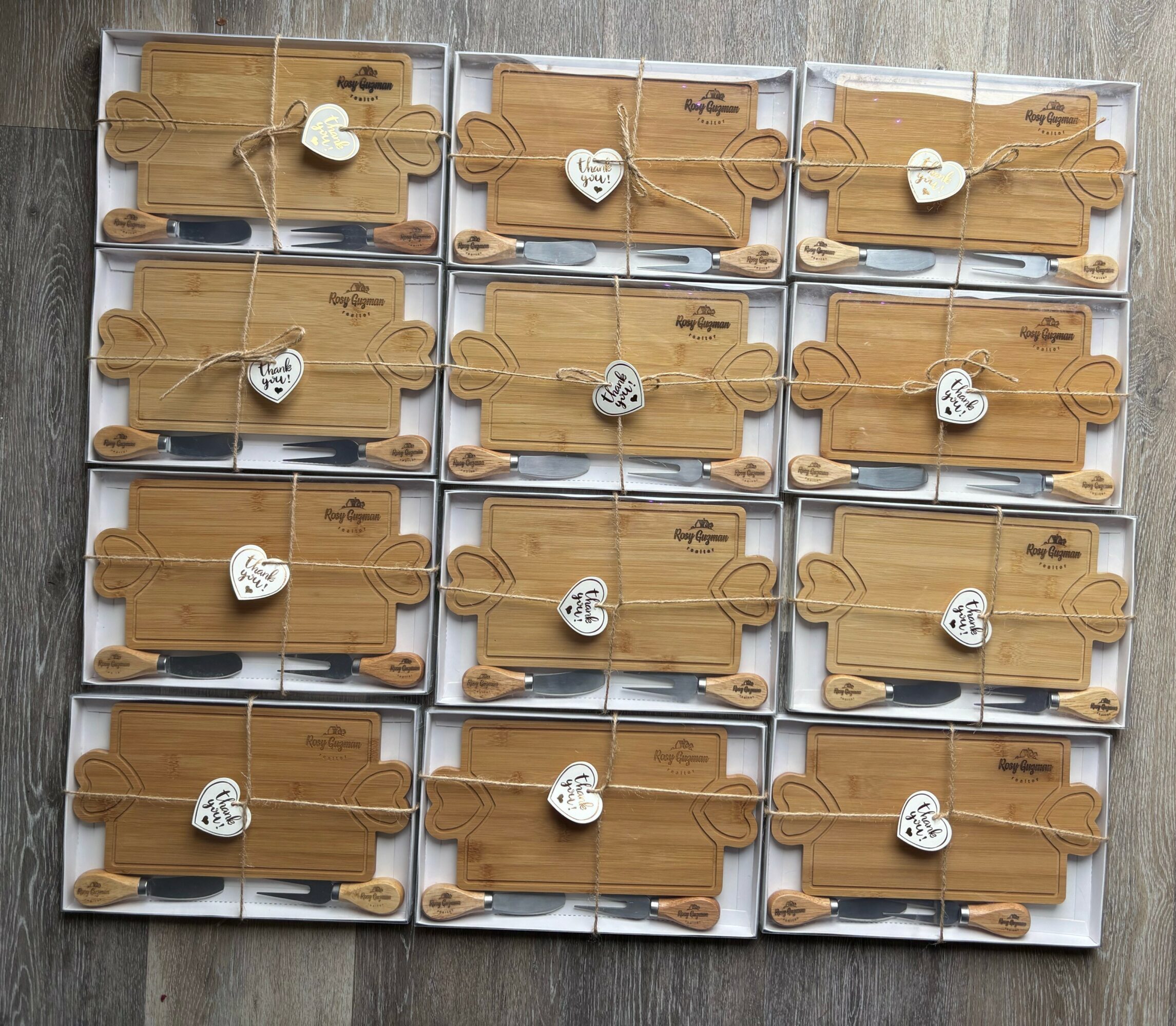 Nine wooden boards with white heart-shaped decorations and black pens, arranged in three rows on a gray surface.