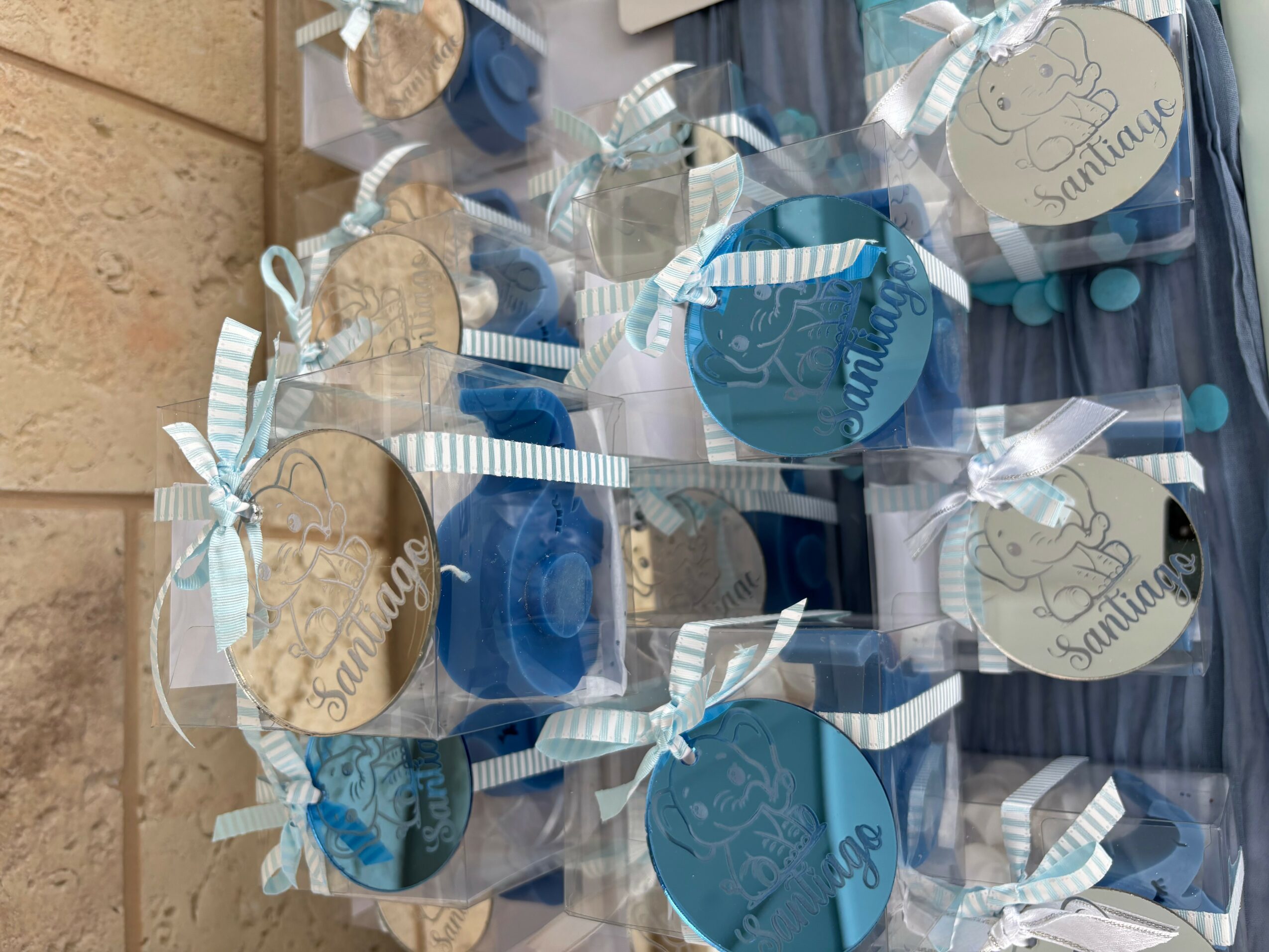 Clear plastic bags with blue and beige circular tags, tied with ribbons, containing small items, arranged on a surface.