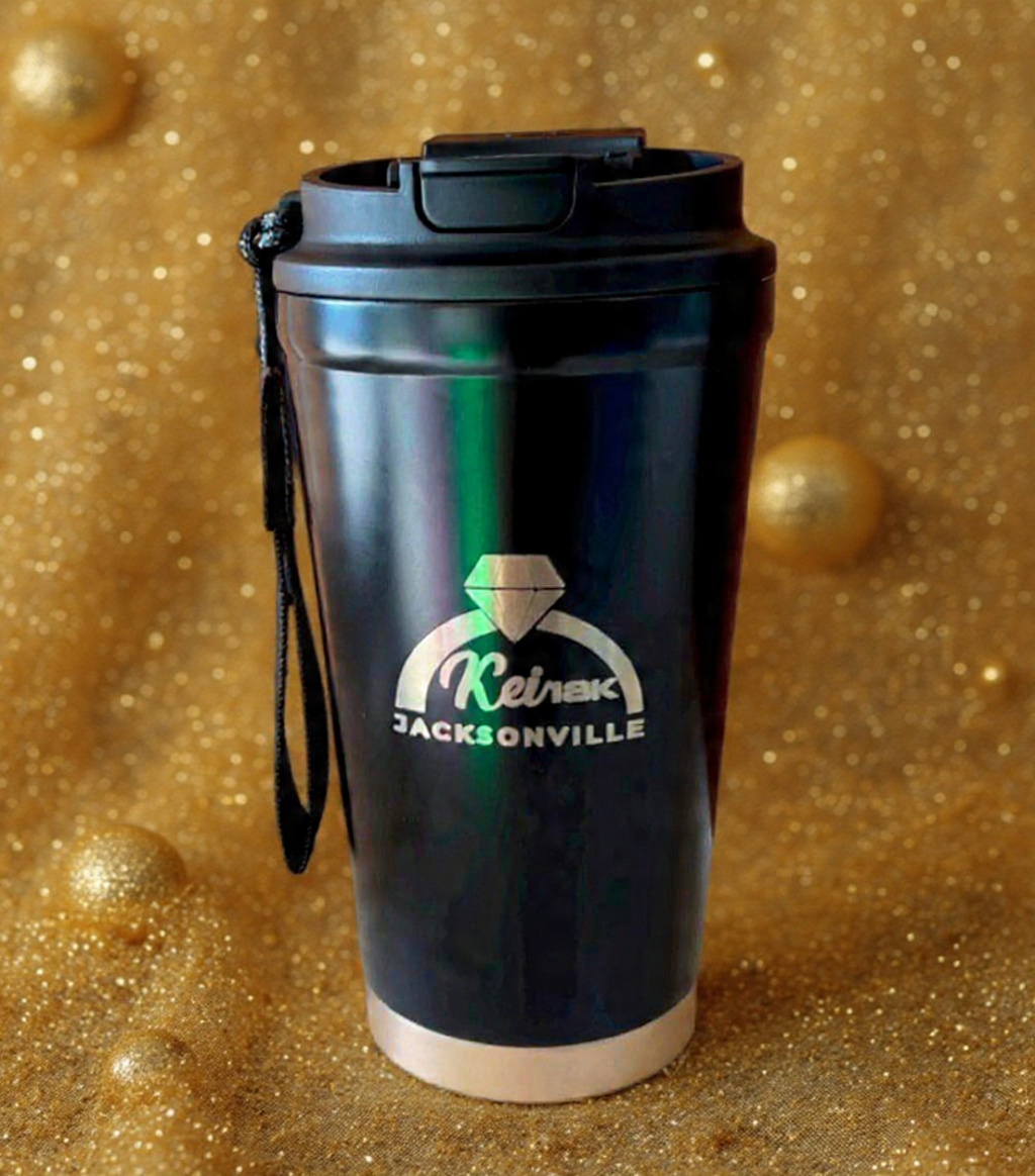 Black travel mug with a logo, set against a gold, glittery background.
