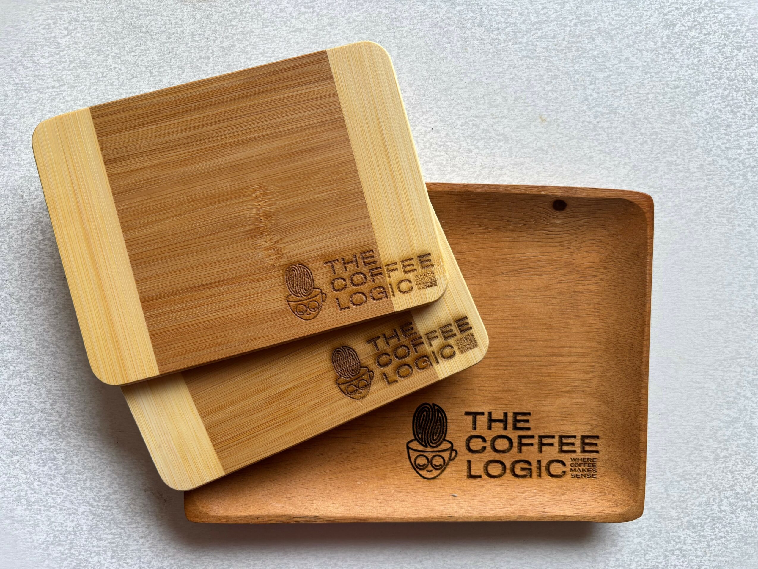 Two wooden coffee trays with a logo and text, one stacked on top of the other, on a light background.