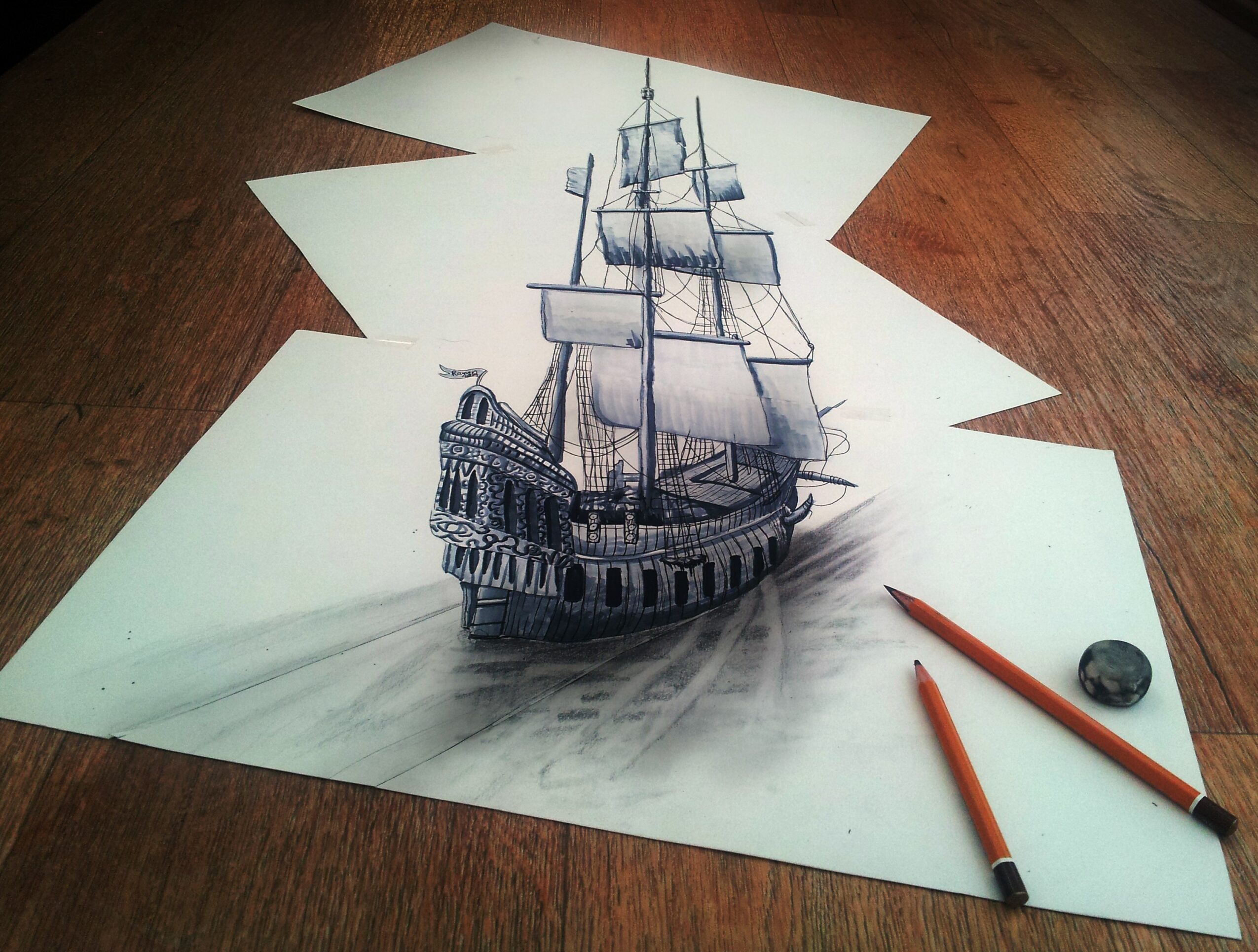 Detailed pencil drawing of a sailing ship on white paper, placed on a wooden surface with drawing tools nearby.