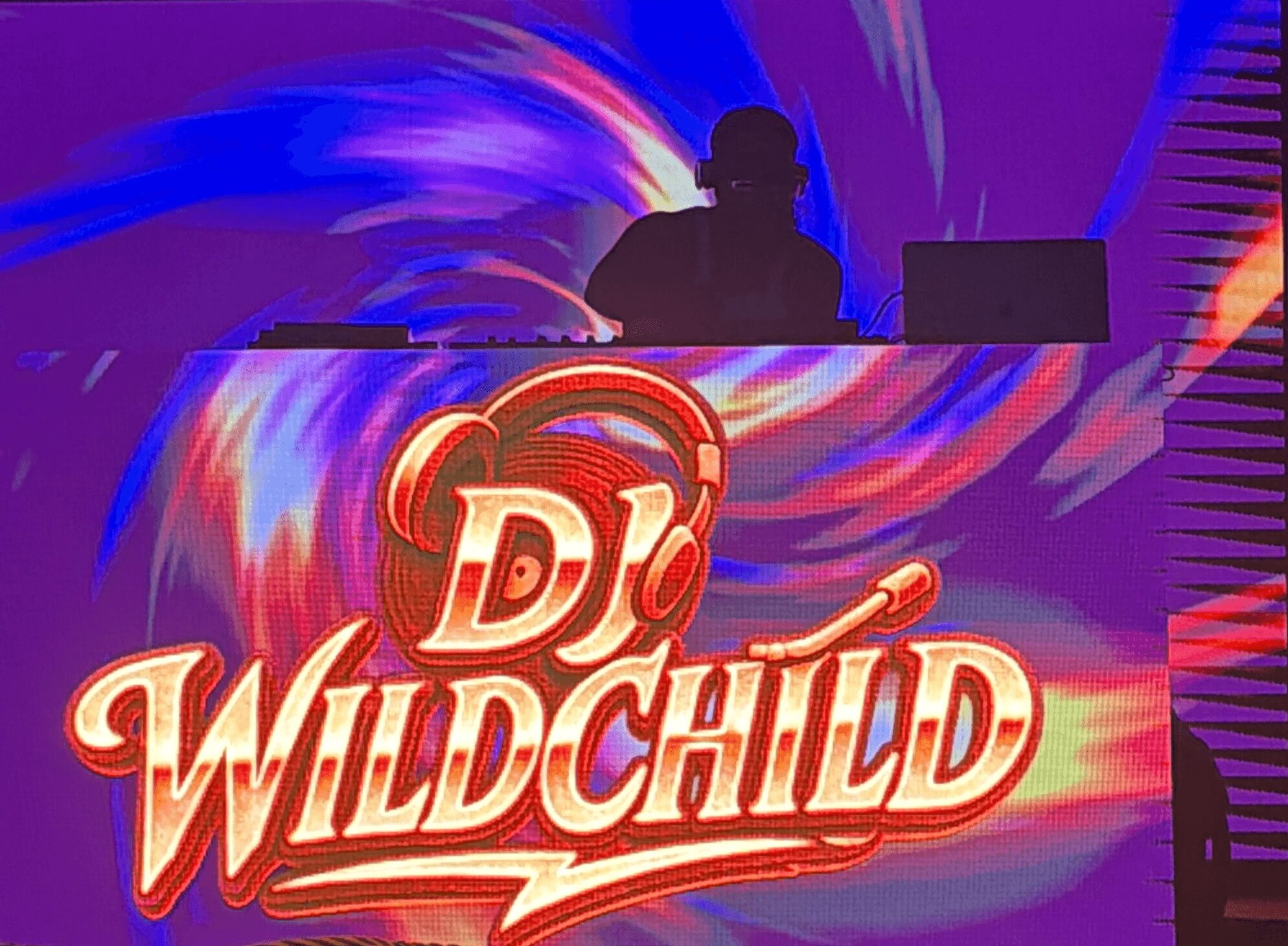 Silhouette of a DJ behind a colorful, illuminated DJ booth with the text 'DJ WILD CHILD' in bright, bold letters.