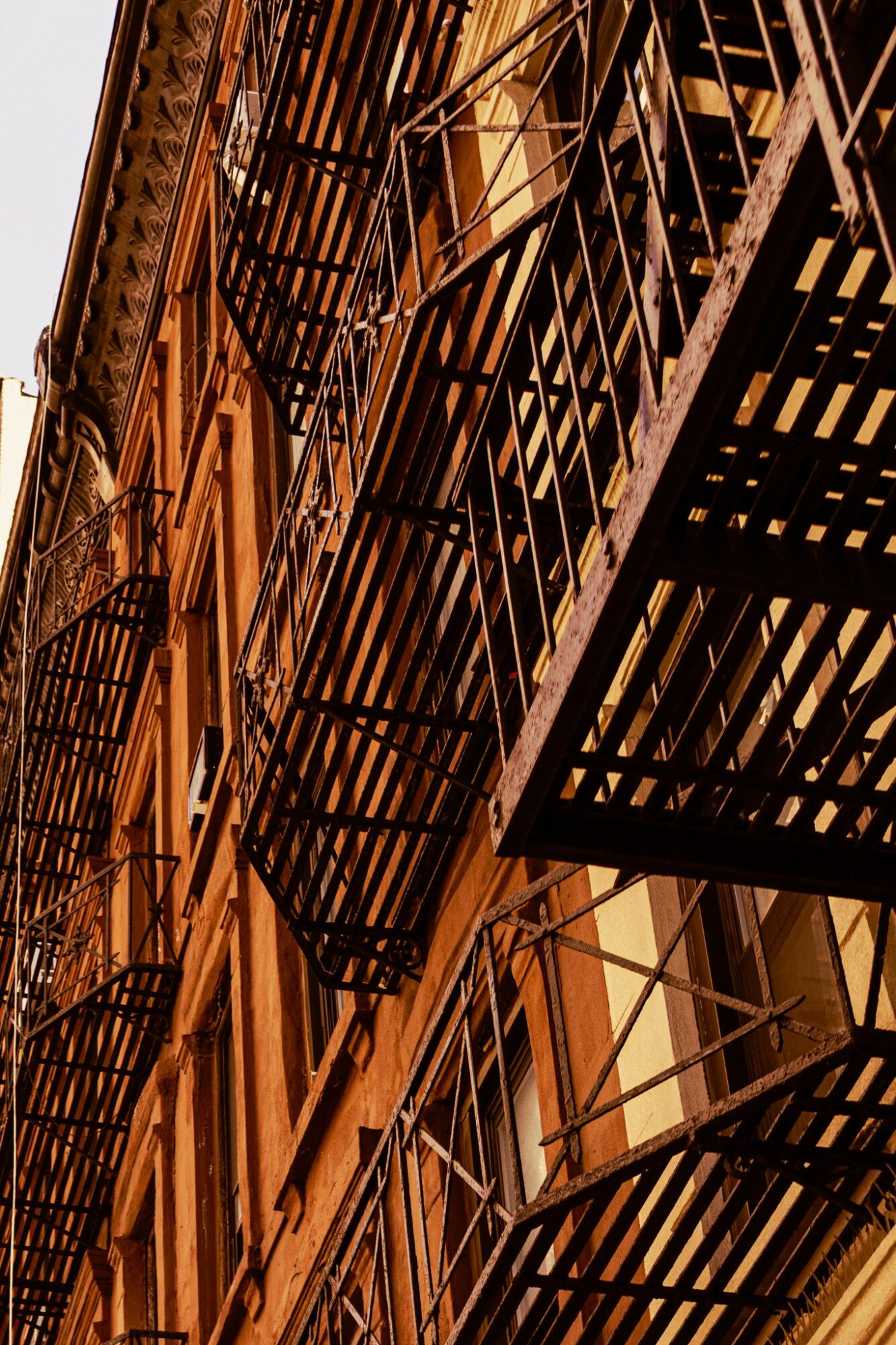 Fire escapes on a building's exterior with metal stairs and railings, viewed from below at an angle.
