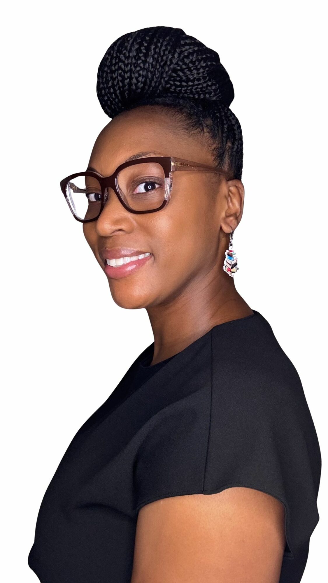 Woman with glasses and braided bun hairstyle, smiling, wearing a black top, earrings visible.