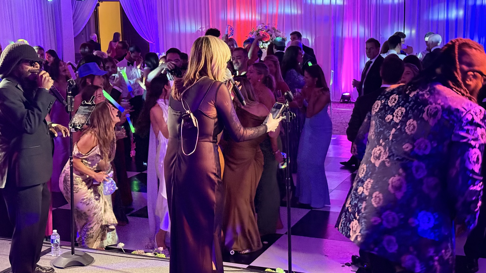 People dancing and socializing at a lively indoor party with colorful lighting.