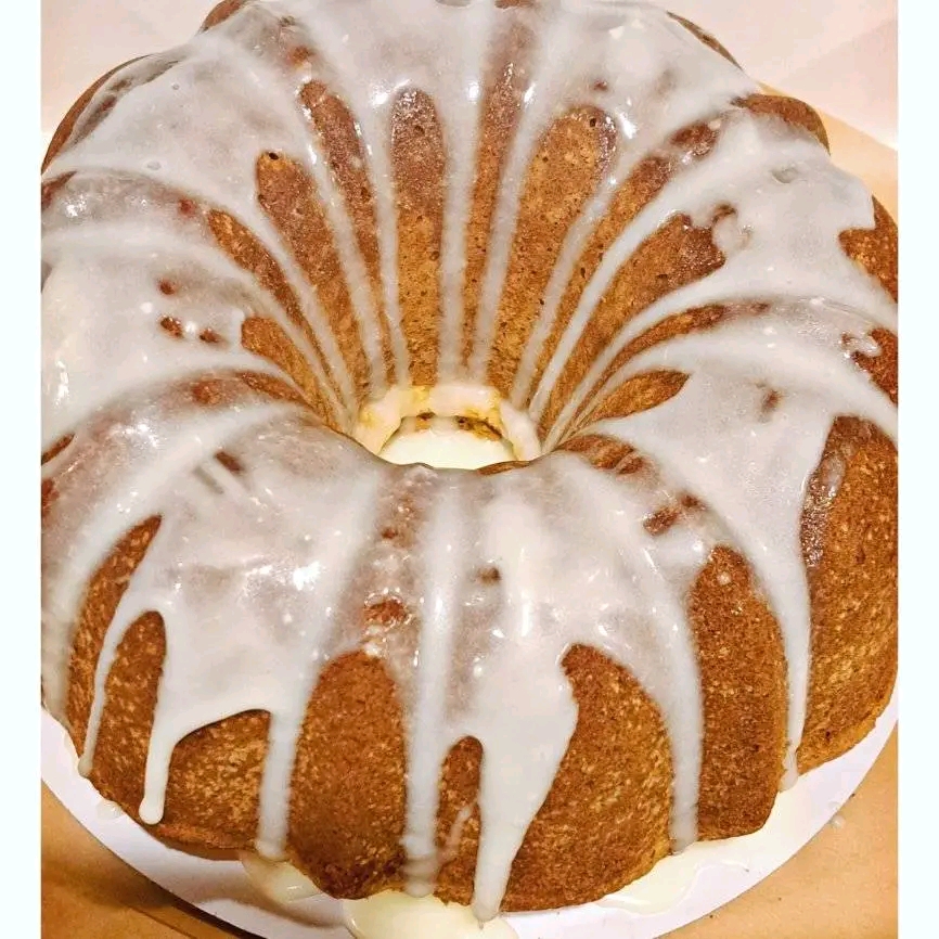 Bundt cake with white icing drizzled over top, displayed on a white plate.