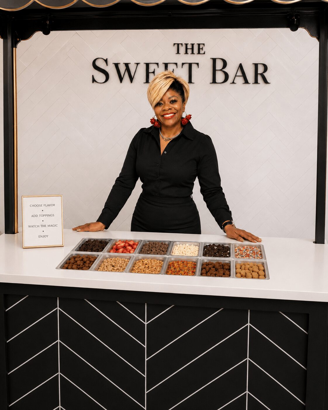 Smiling woman standing behind a display of assorted sweets at a bar named 'The Sweet Bar'.