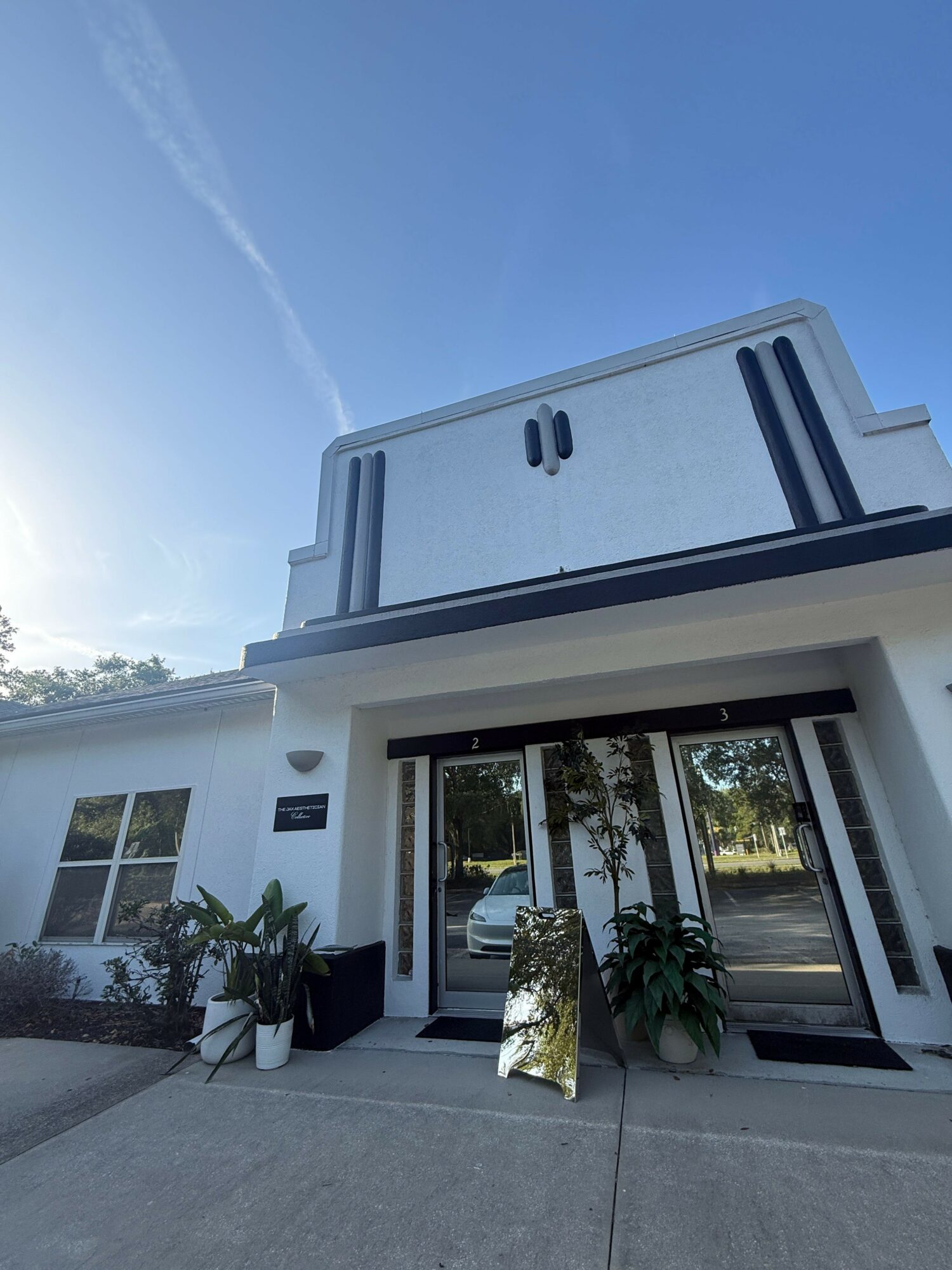 Front view of a modern house with large glass doors and potted plants outside.