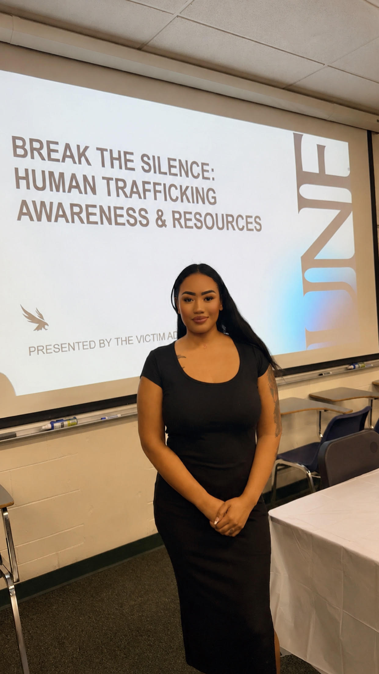 Young woman standing in front of a presentation slide about human trafficking awareness and resources.