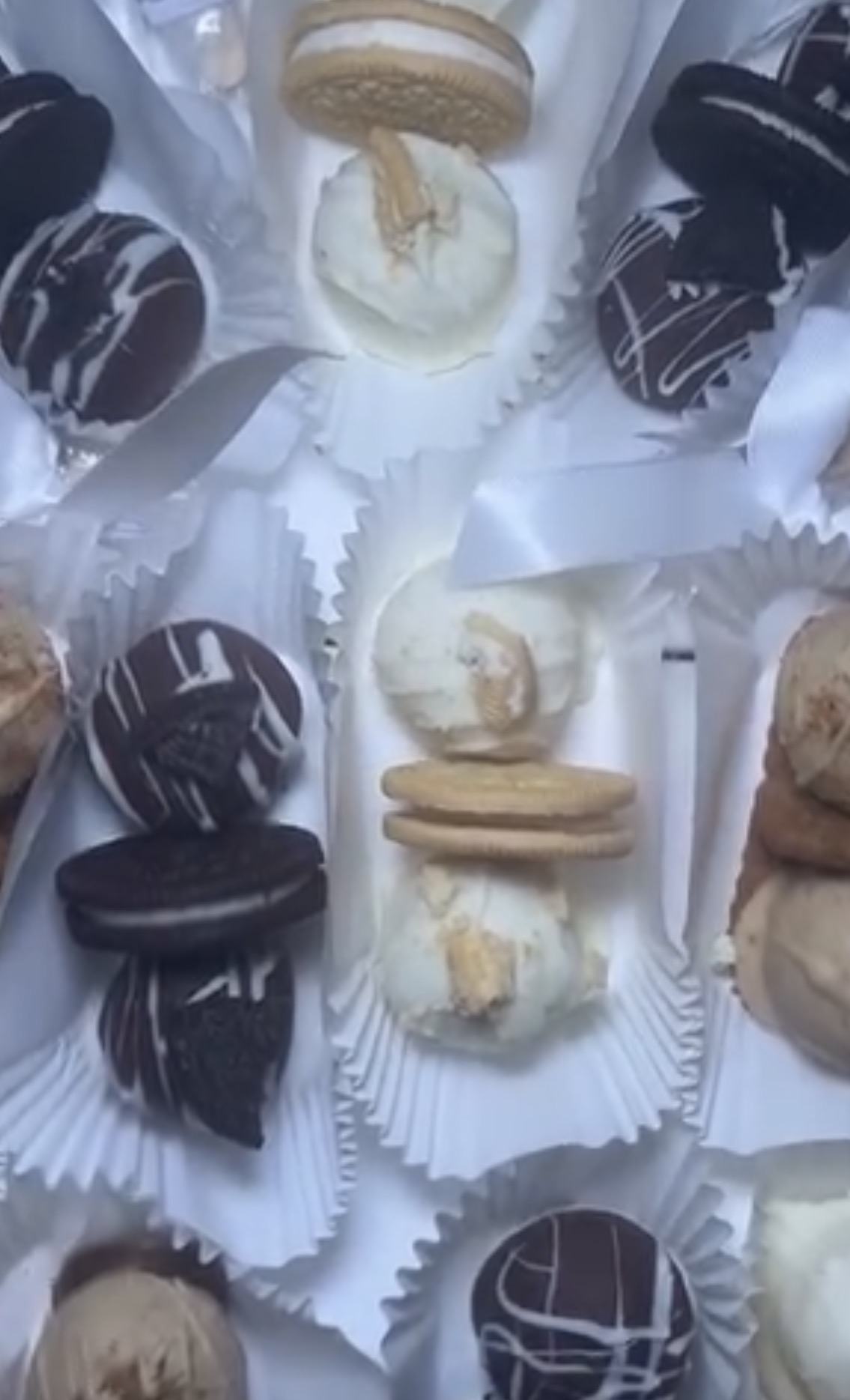 Assorted cookies and desserts on white paper, some with chocolate and cream, arranged in a circular pattern.
