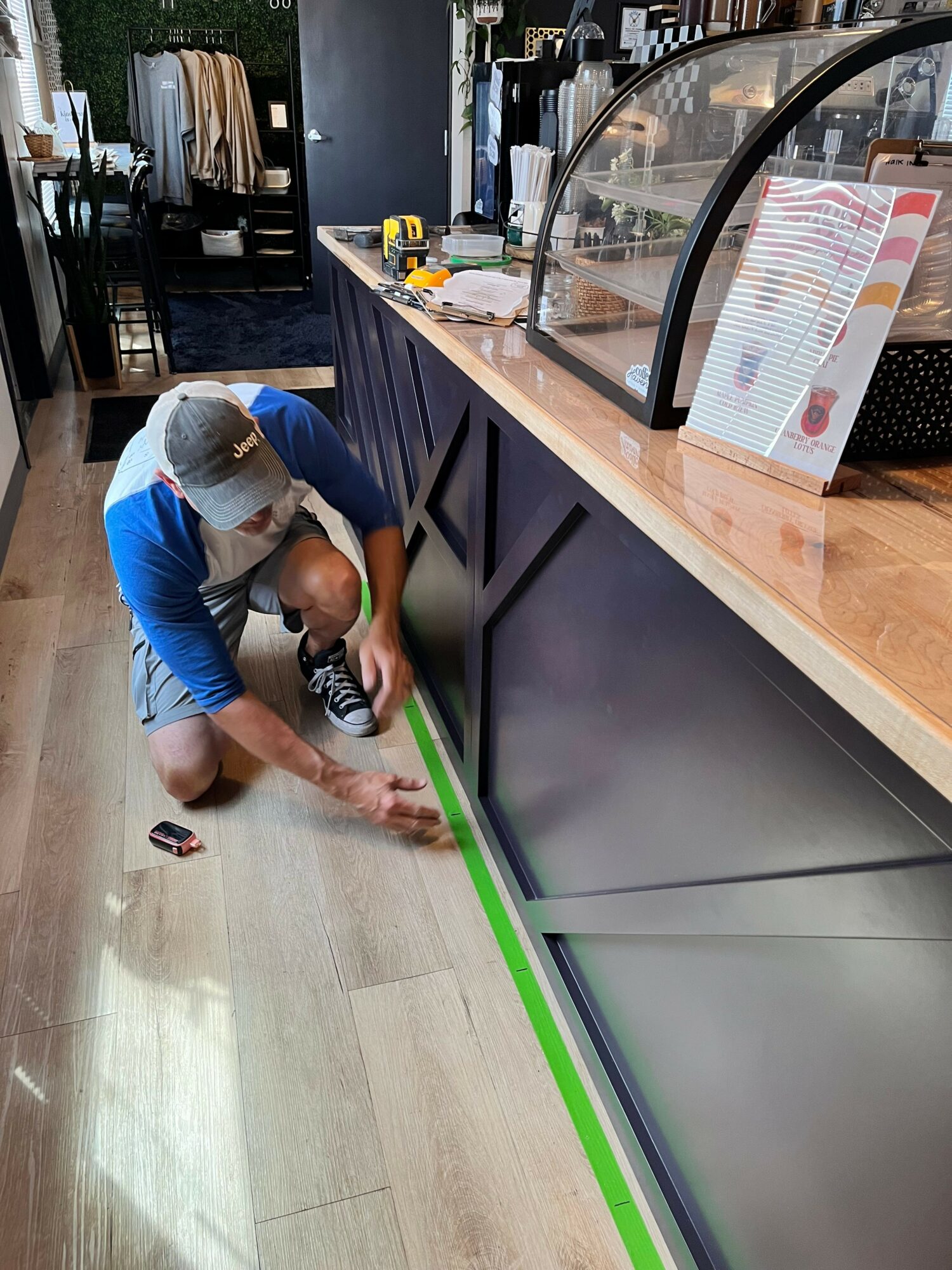 Person cleaning a black counter with a green edge in a room with wooden flooring.