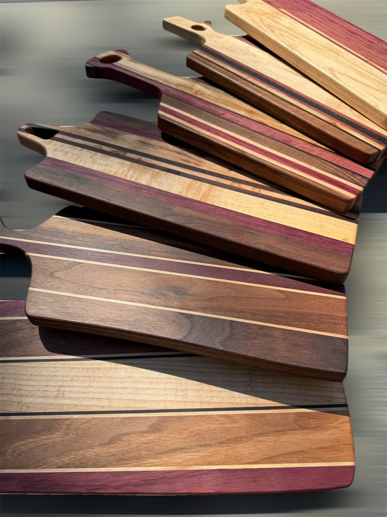 Multiple wooden cutting boards with different wood grain patterns and colors, arranged on a surface.