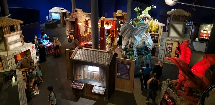 Museum exhibit with miniature buildings, a dragon sculpture, and visitors exploring displays.