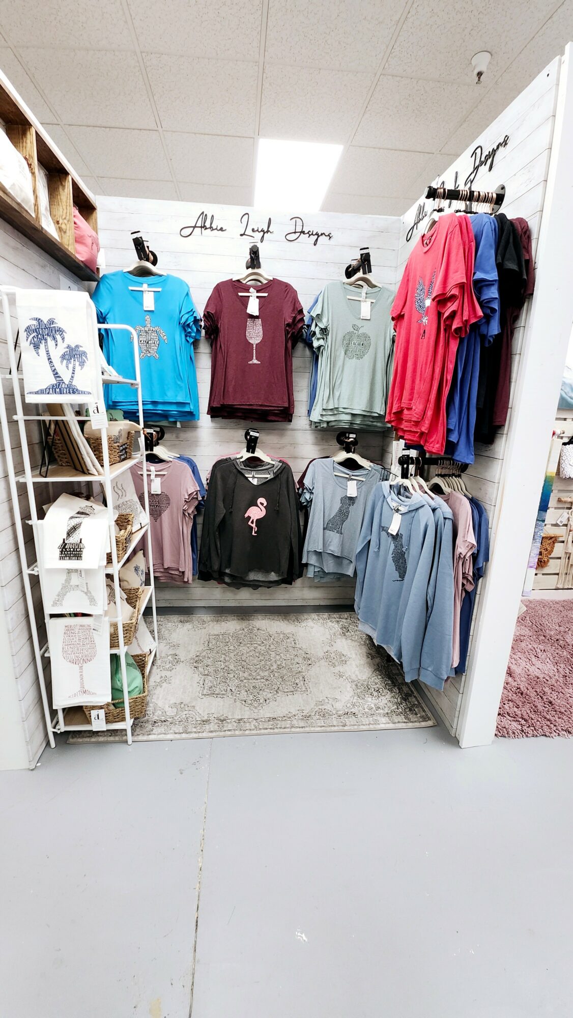 Display of colorful scrubs and medical uniforms on mannequins and racks in a store, with shelves on the side and a sign above.