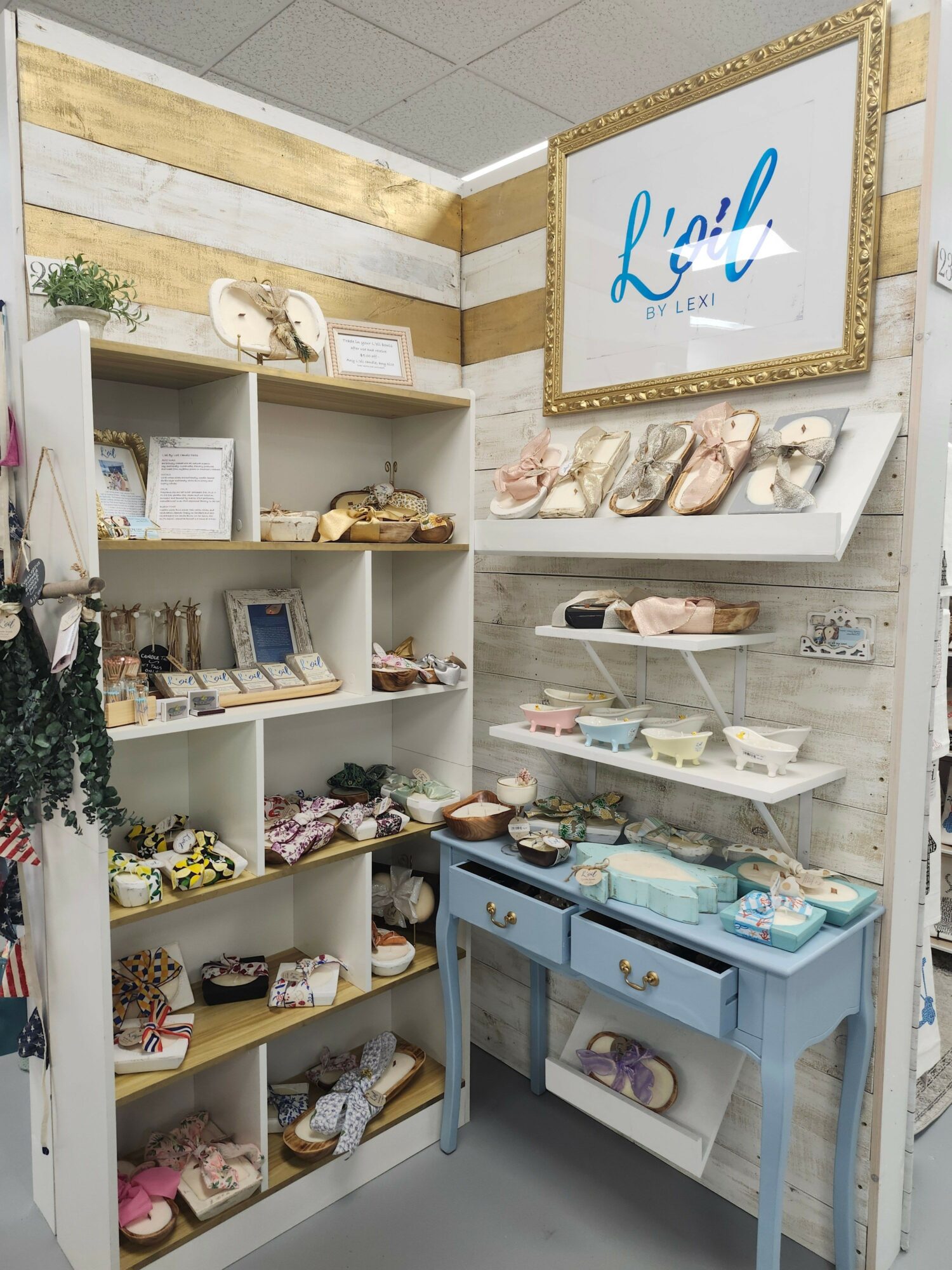 Display of plush toys and decorative items in a store with a framed sign reading 'Lilly'.