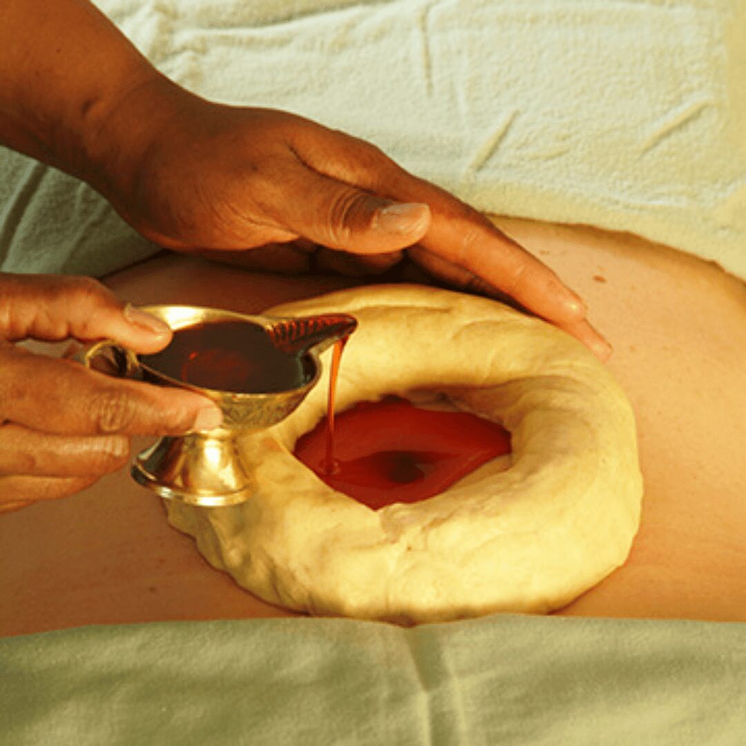 Person pouring red liquid into a dough ring with a hole in the center, on a wooden surface.