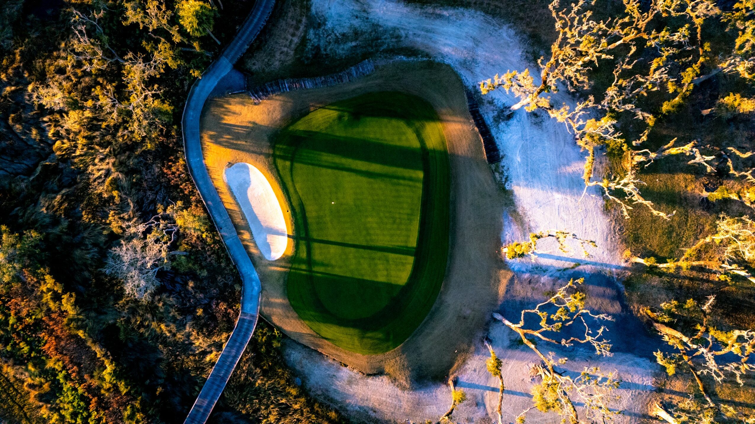 A circular water reservoir with a walkway, surrounded by trees and a waterfall, viewed from above.