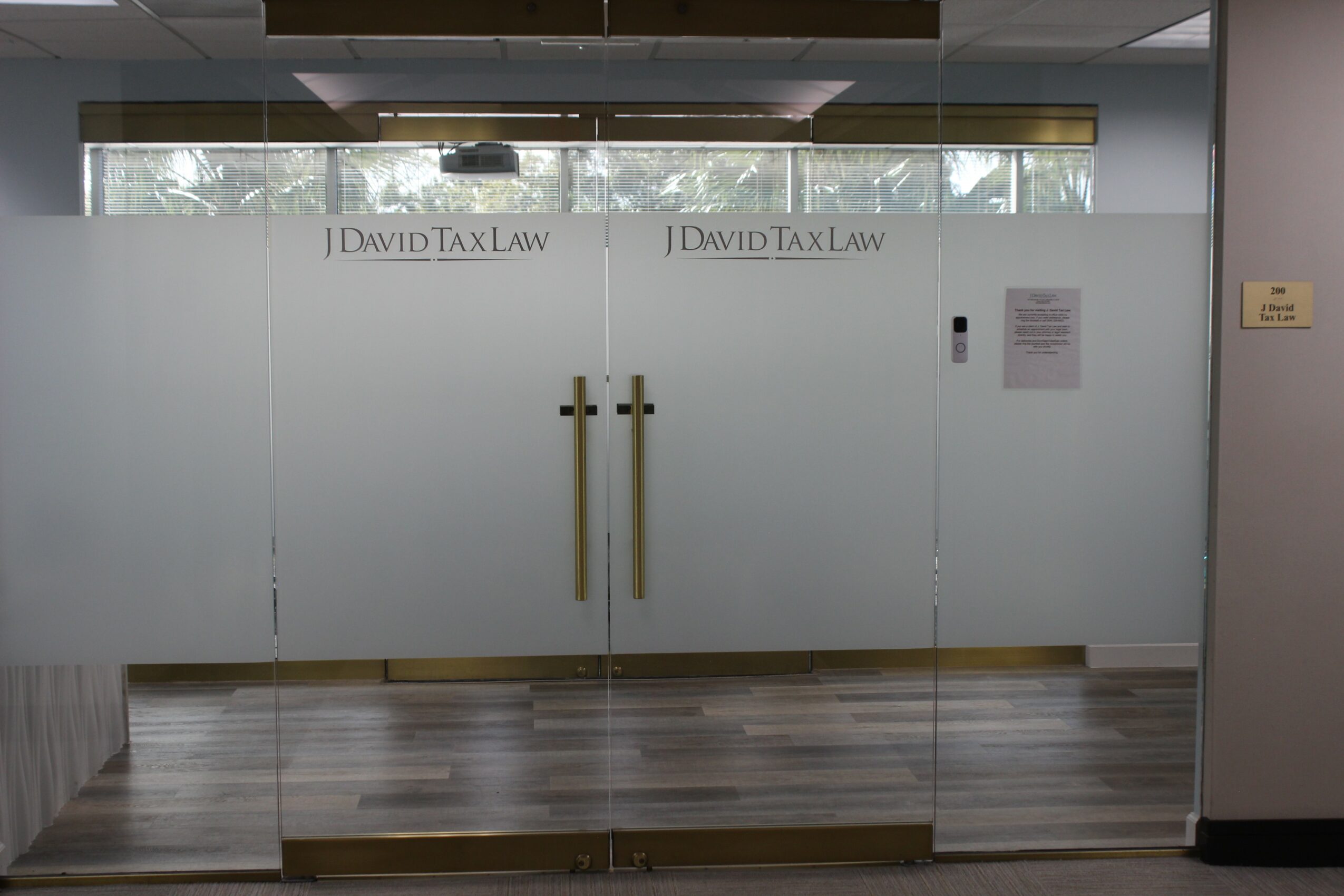 Glass doors with handles and signs reading 'David Tax Law' inside an office building.